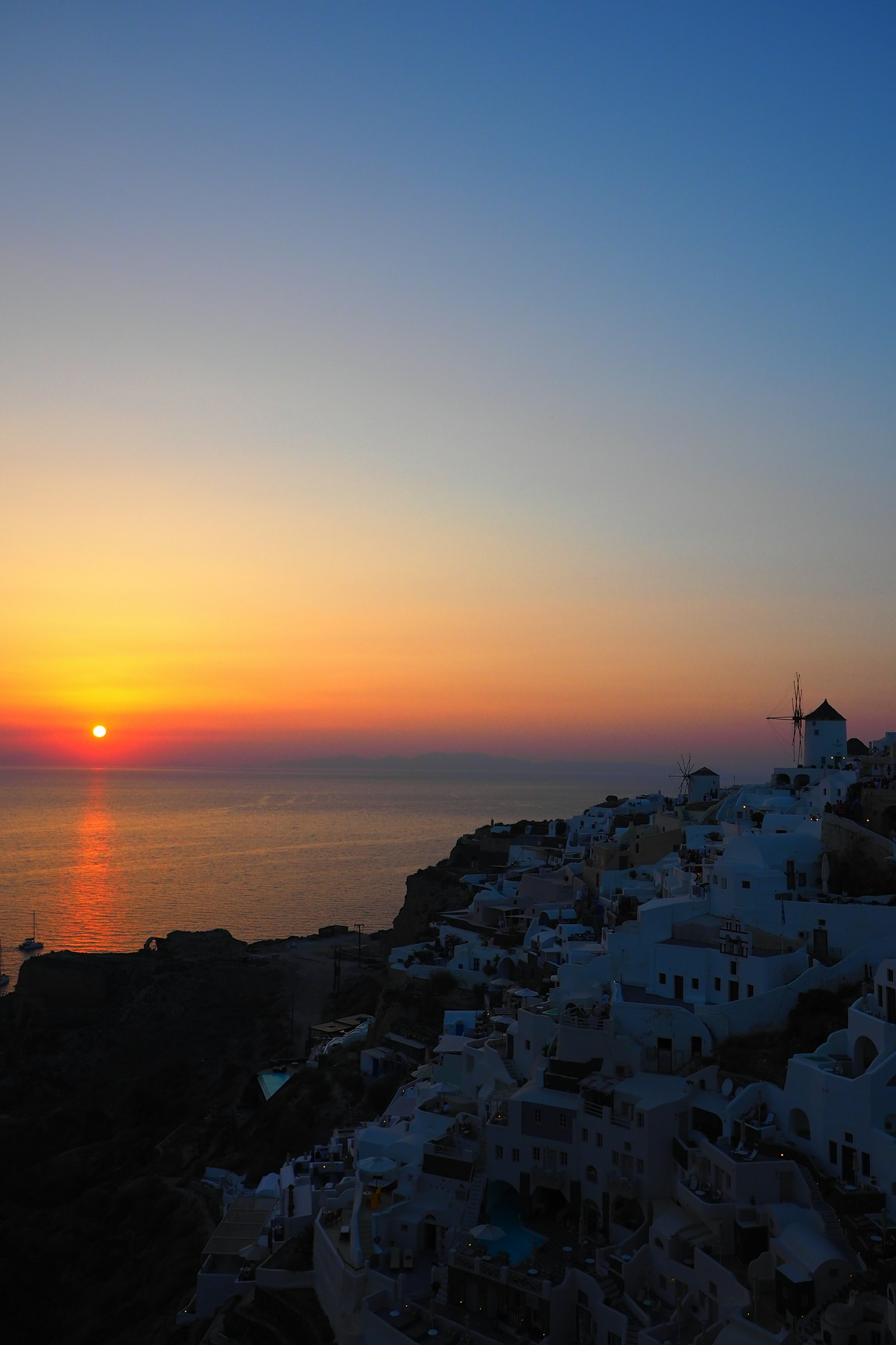 Wunderschöner Sonnenuntergang über dem Meer in Santorin weiße Gebäude auf einem Hügel