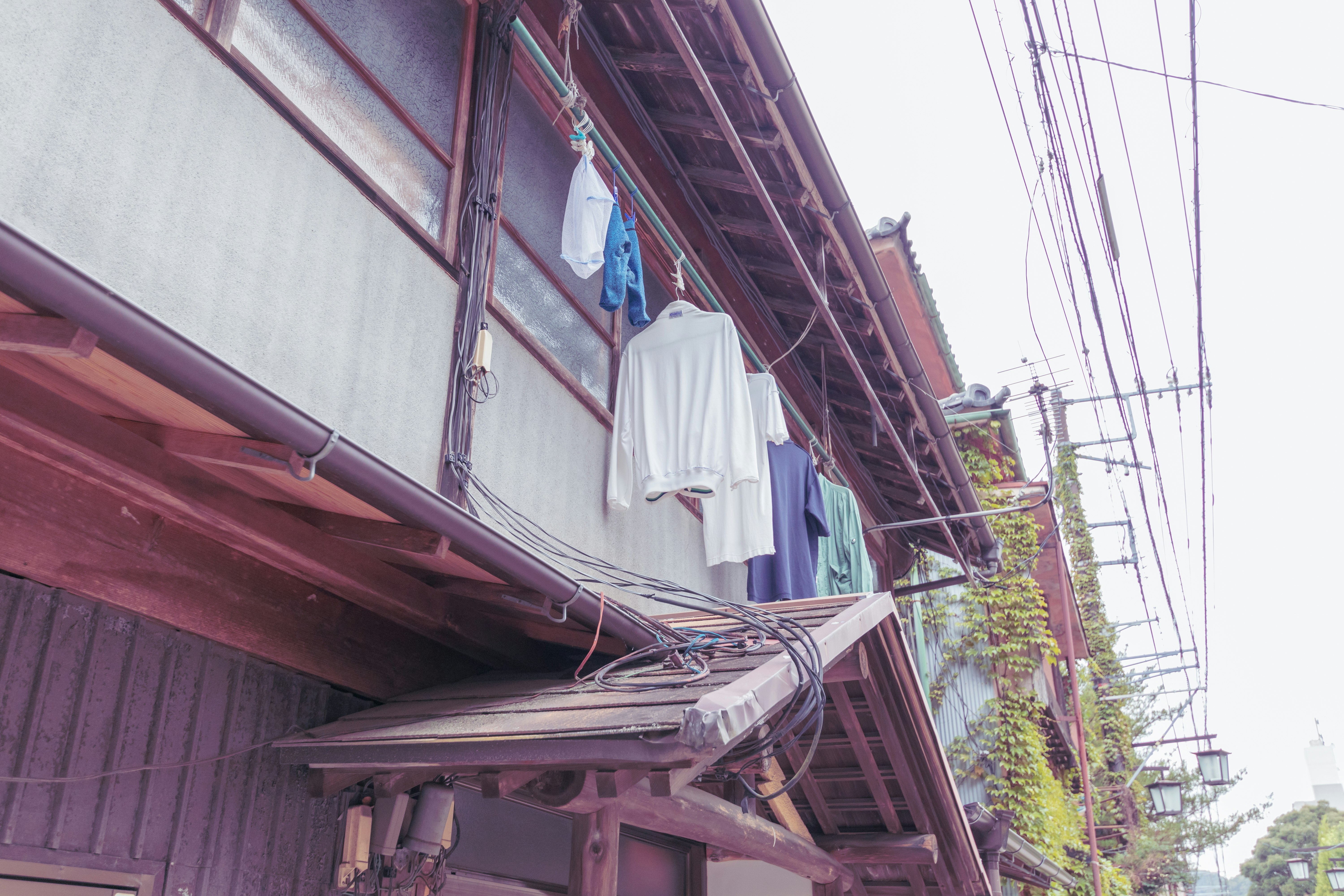 路地の民家の軒先に並ぶ洗濯物とレトロな建物