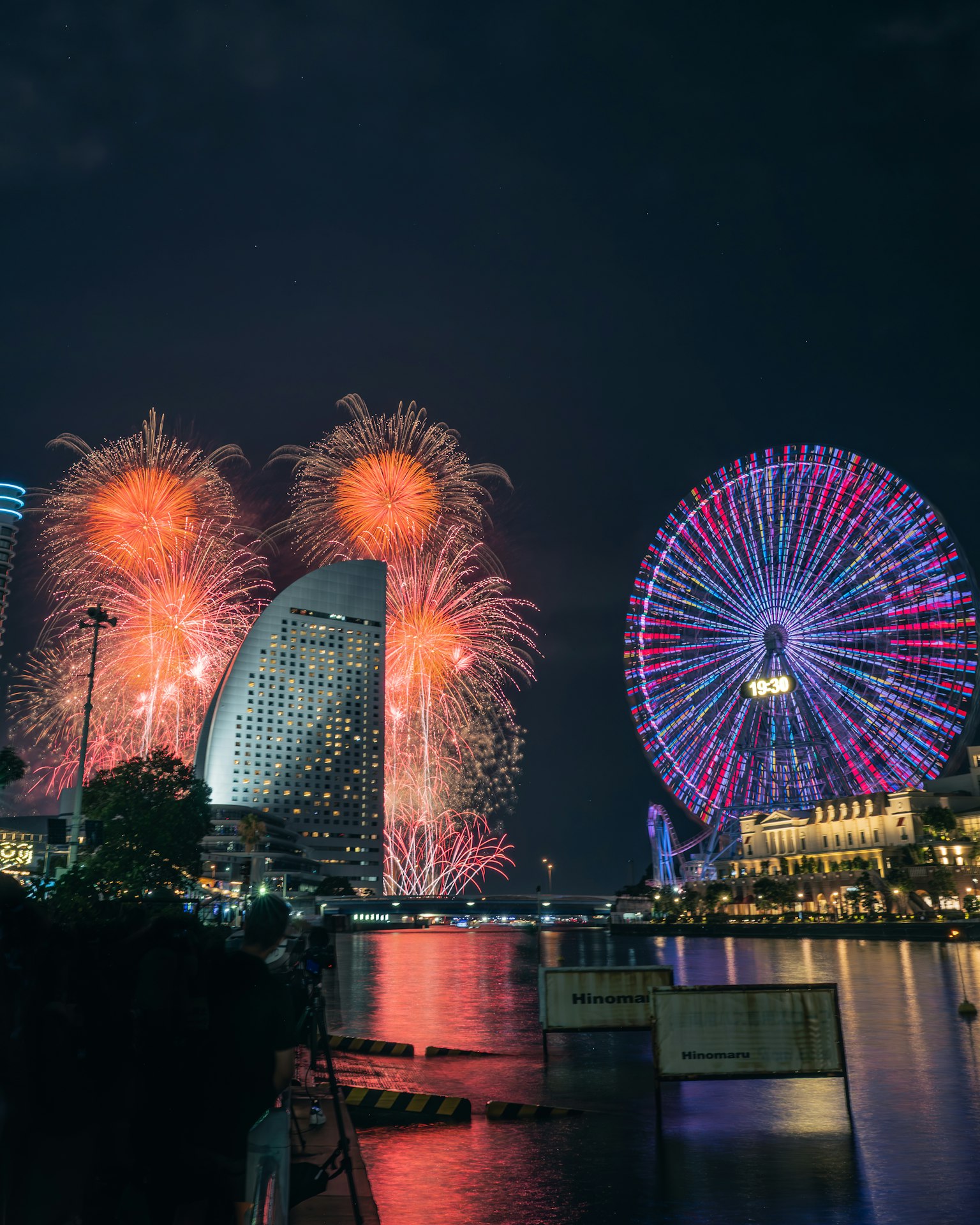 Fuochi d'artificio illuminano il cielo notturno di Yokohama con una ruota panoramica e edifici moderni