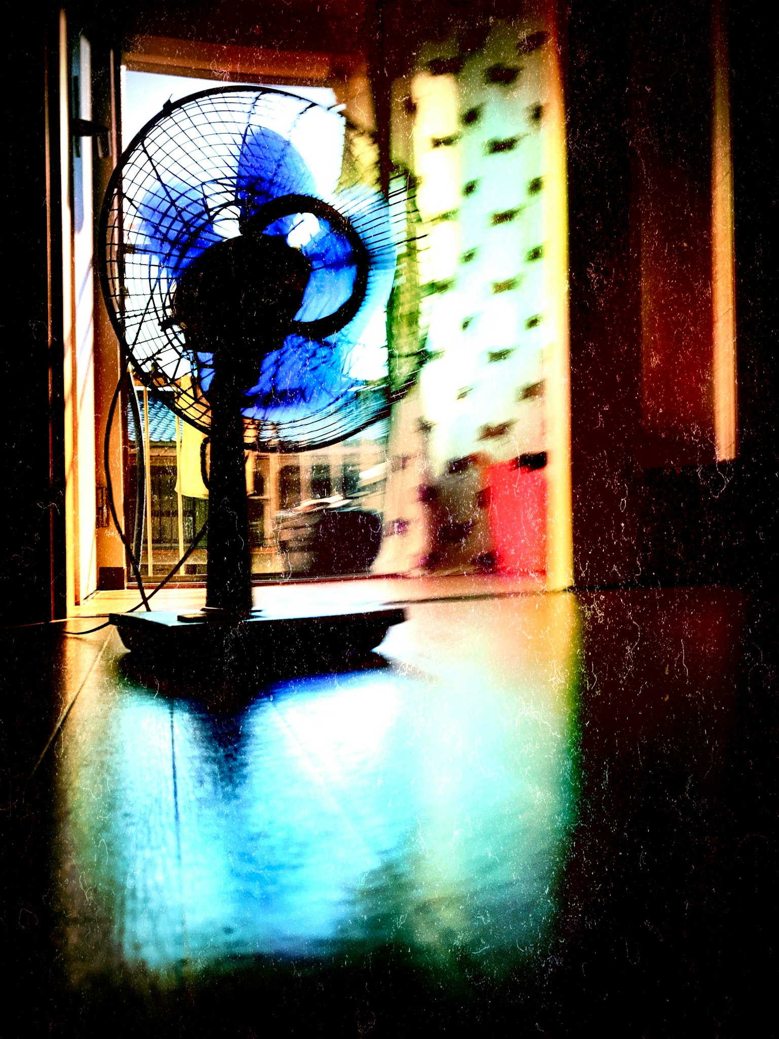 Indoor scene featuring a rotating fan with blue blades and reflections on the floor