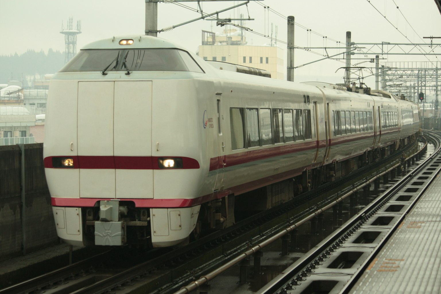 一列光滑的白色火車上有紅色條紋在軌道上行駛