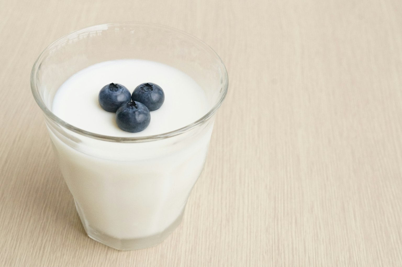 Un vaso de yogur cubierto con tres arándanos