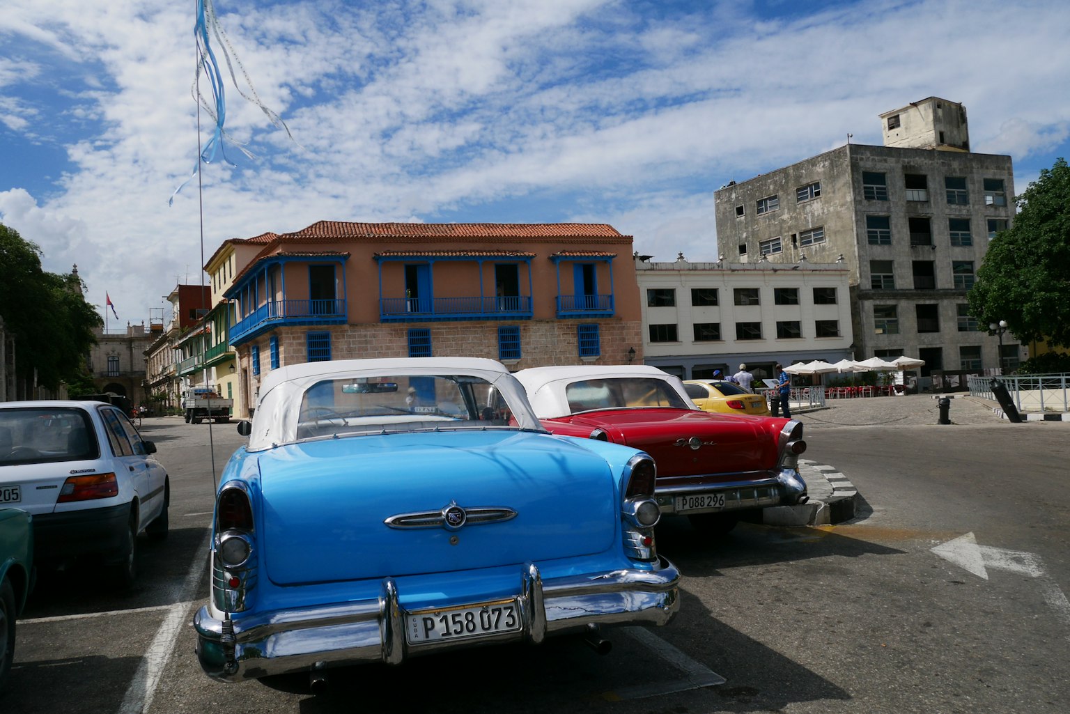 Blaues Oldtimerauto und rotes Oldtimerauto in einer Stadtszene geparkt