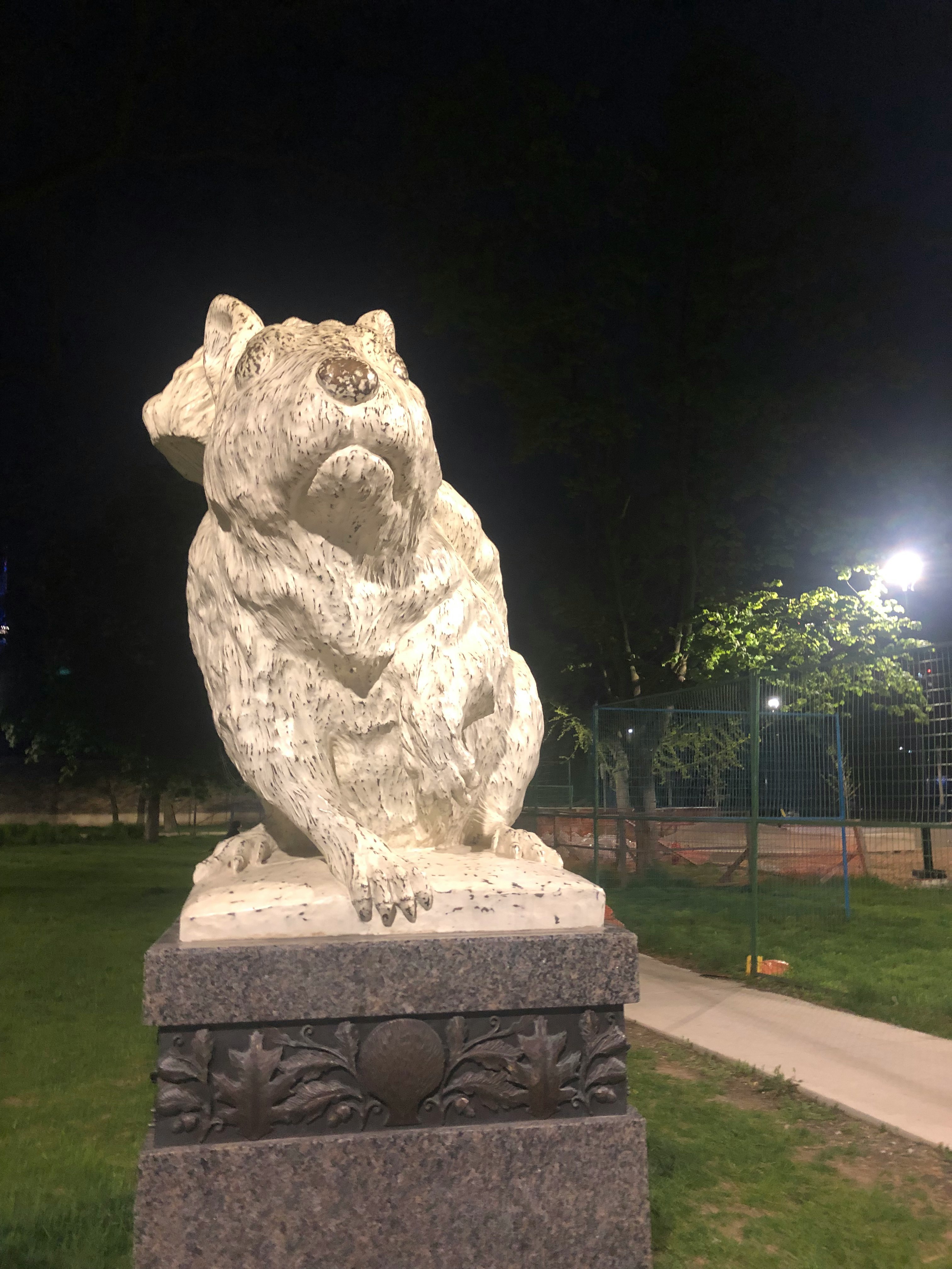 stone dog statue lit by a park light at night
