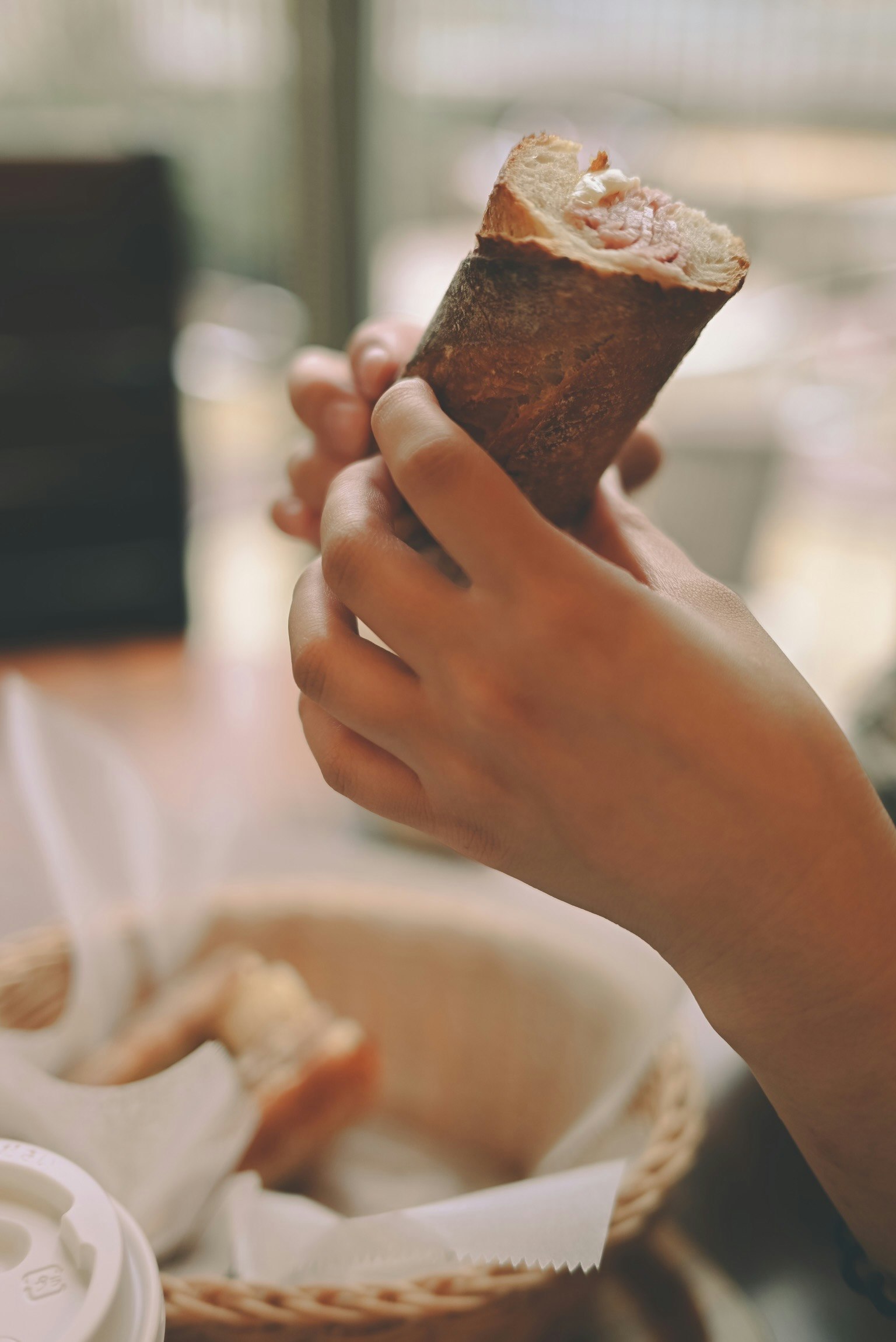 Hände halten ein Eis im Waffelbecher mit Löffel auf einem Tisch
