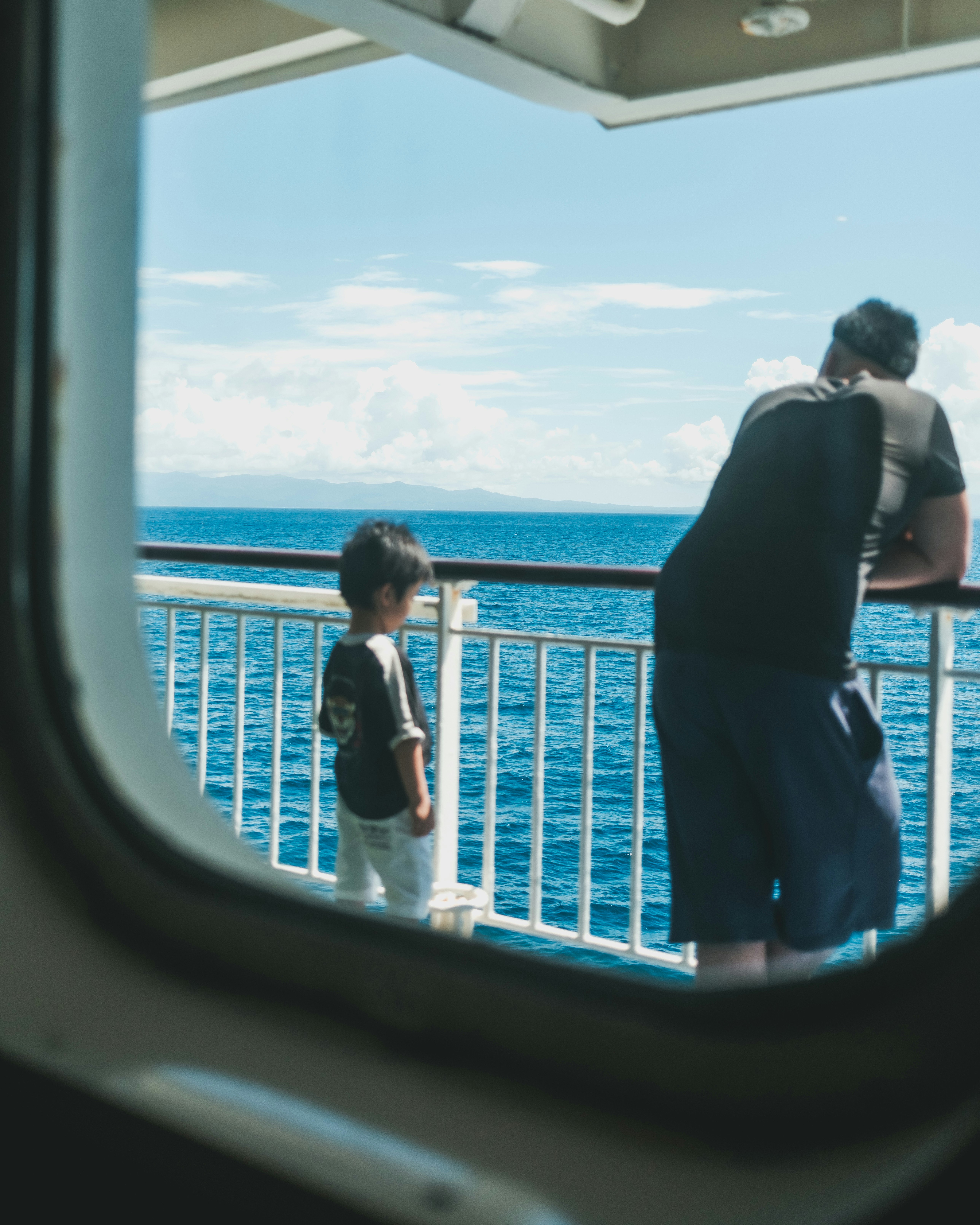 People on a journey looking out a ship window at the blue sea