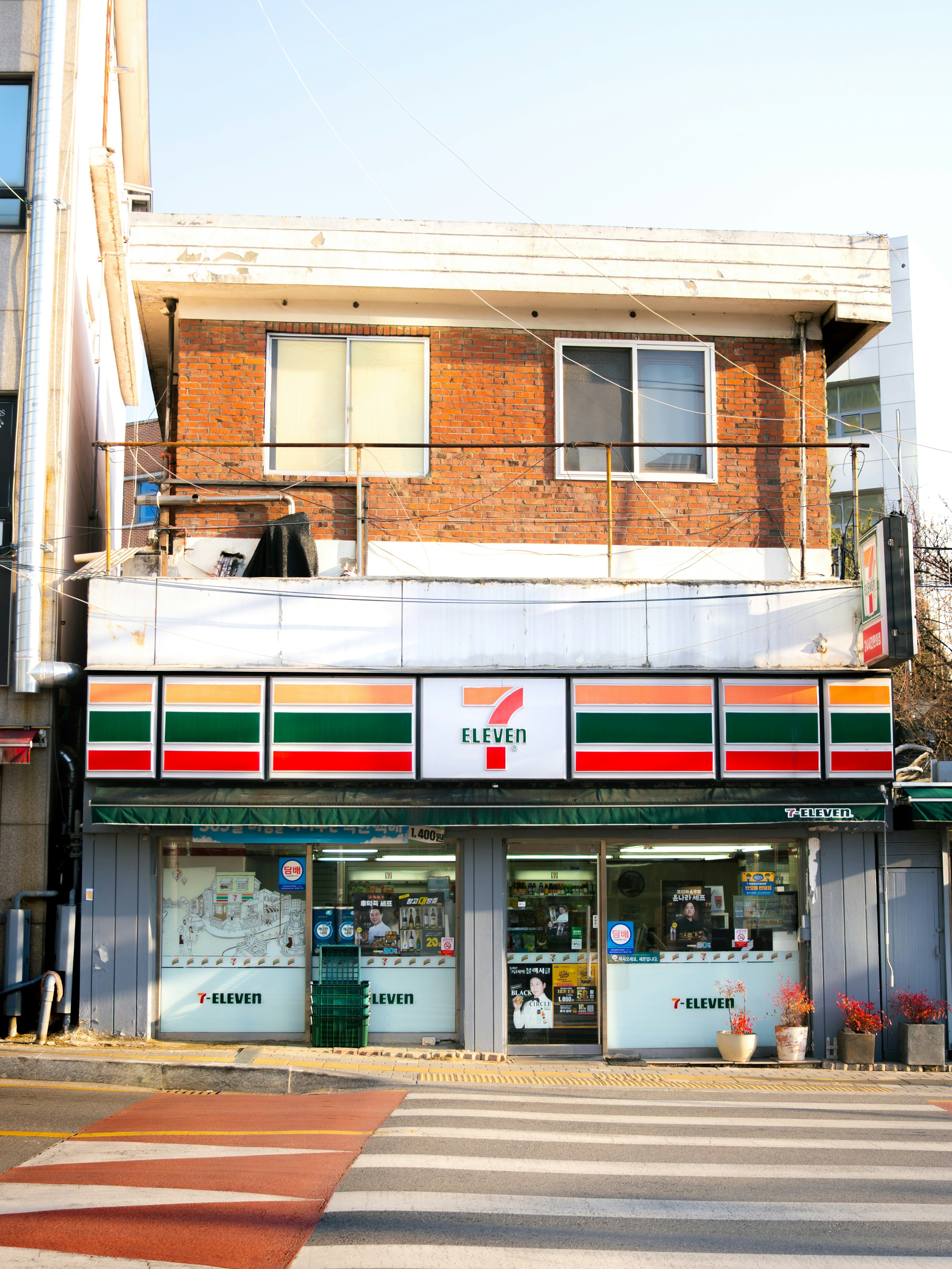 レンガ造りの建物とコンビニの看板が並ぶ街角の風景
