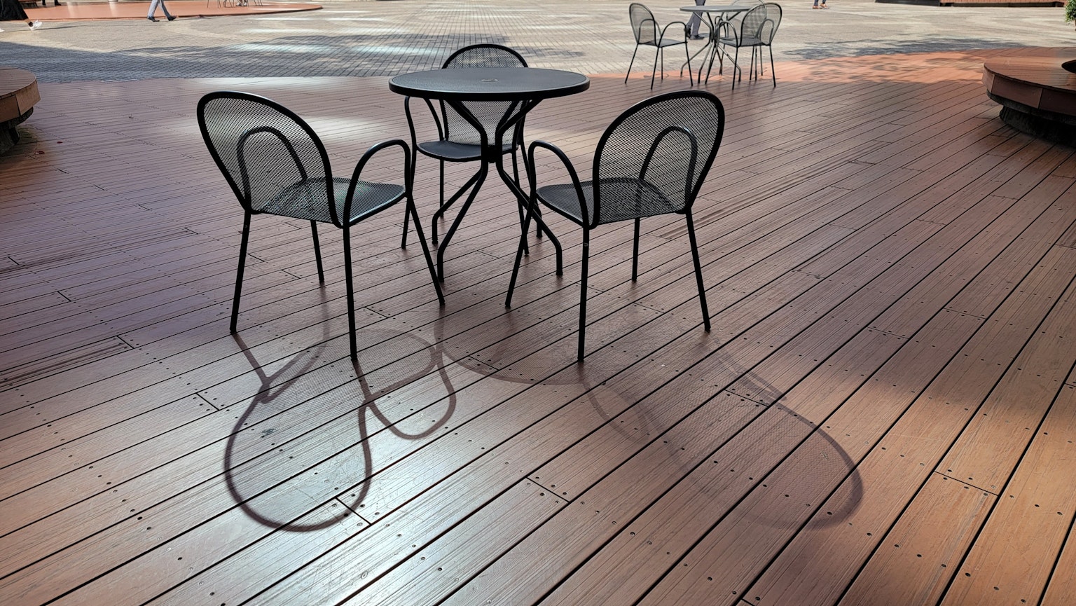 Terraza de madera al aire libre con mesa y sillas de metal negro
