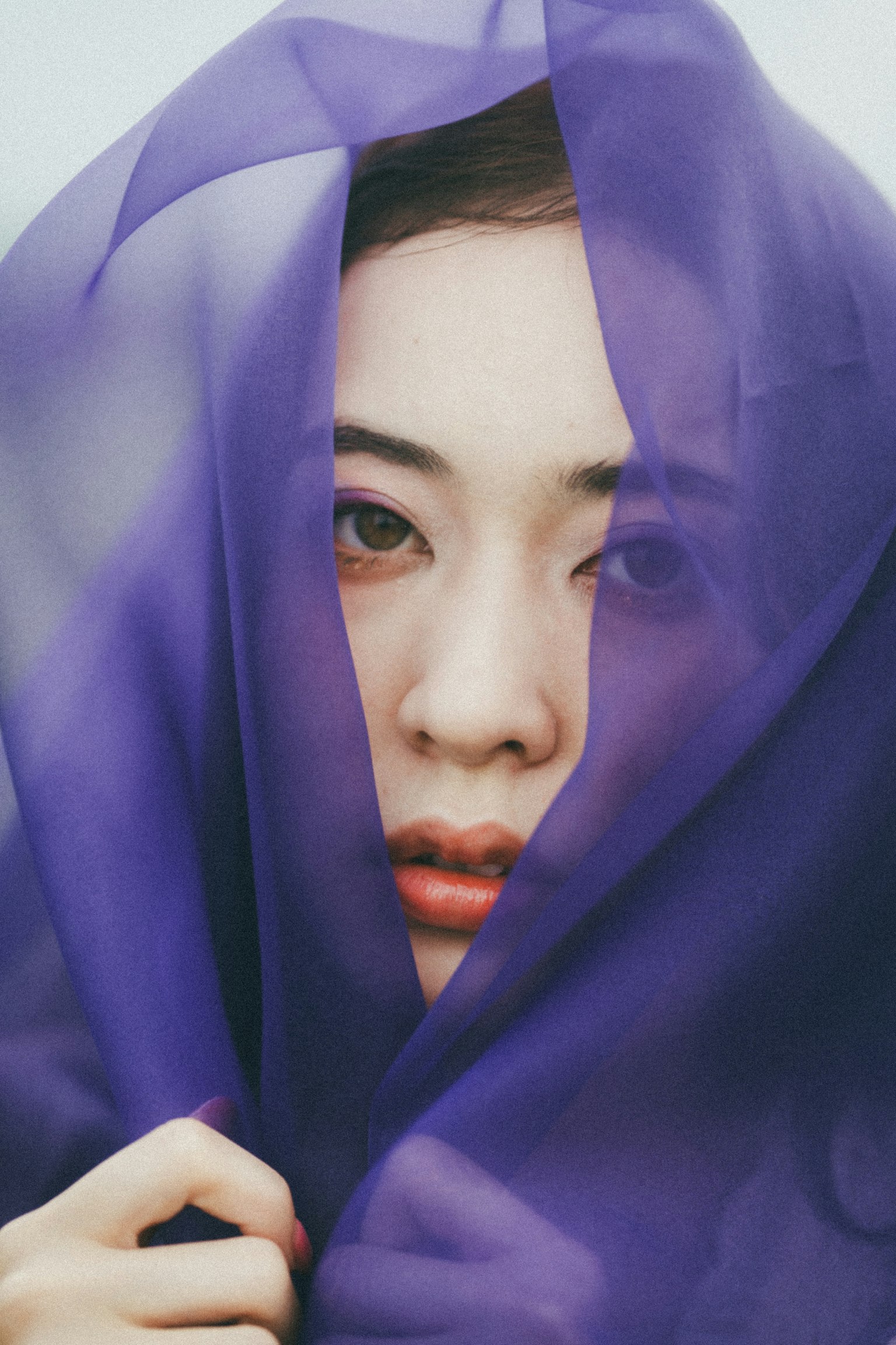 Retrato suave de una mujer con un pañuelo morado cubriendo parcialmente su rostro