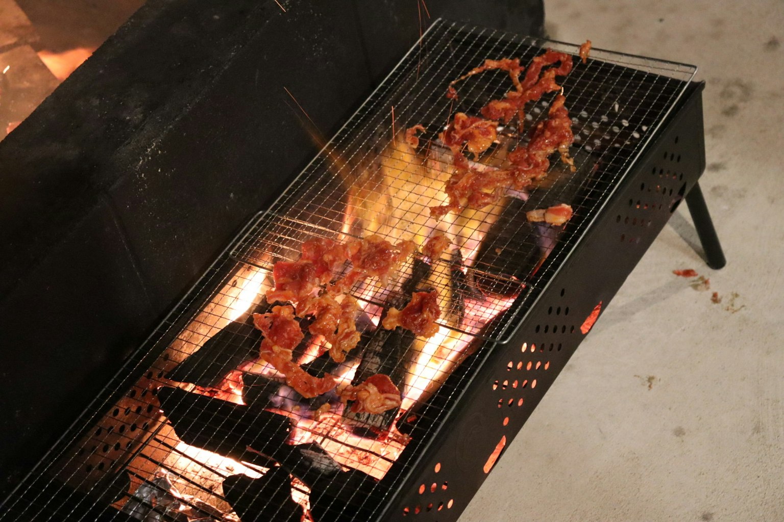 Potongan daging yang dipanggang di atas panggangan arang dengan api
