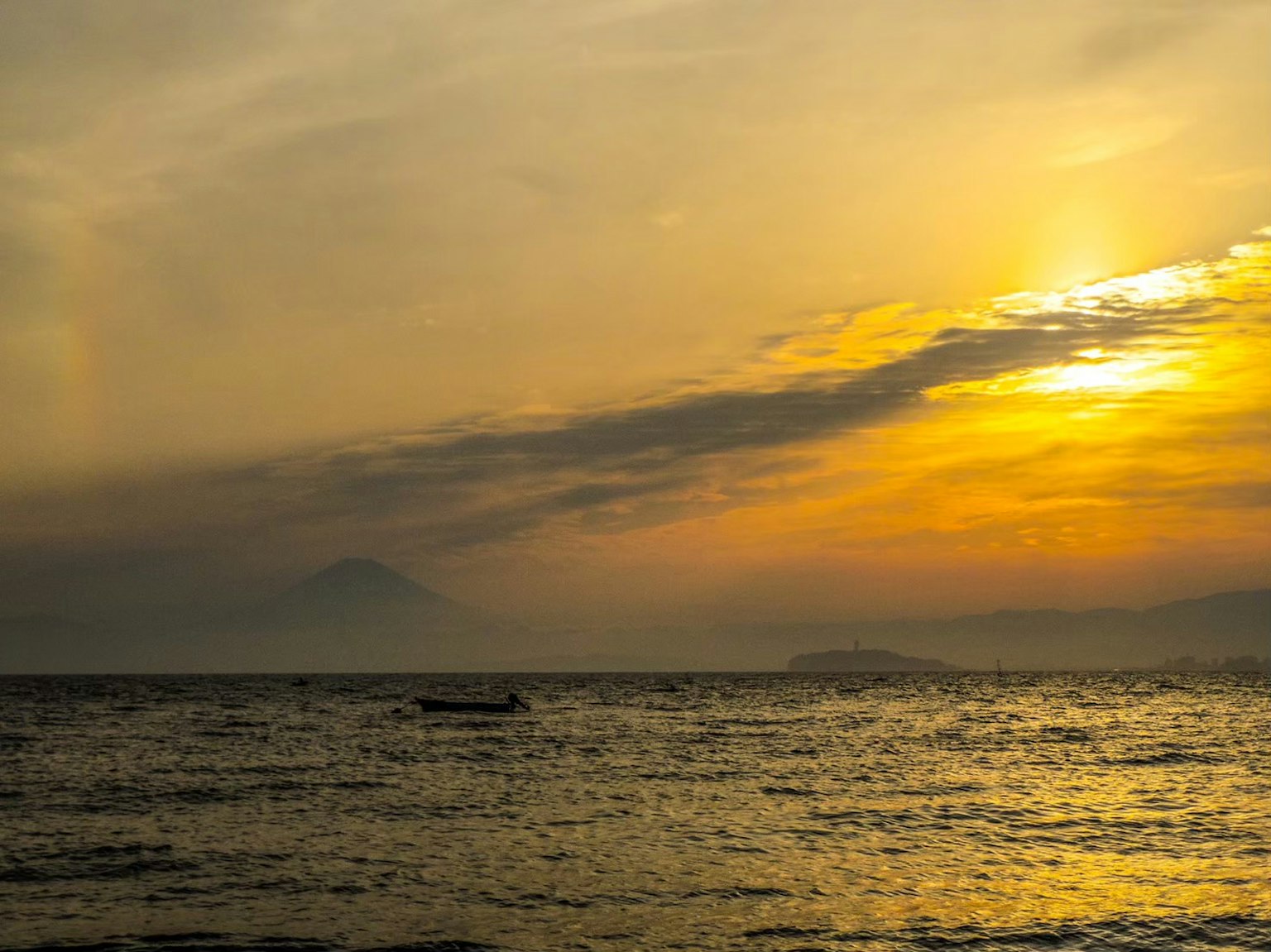 Silhouette of a mountain and a small boat on a sunset sea