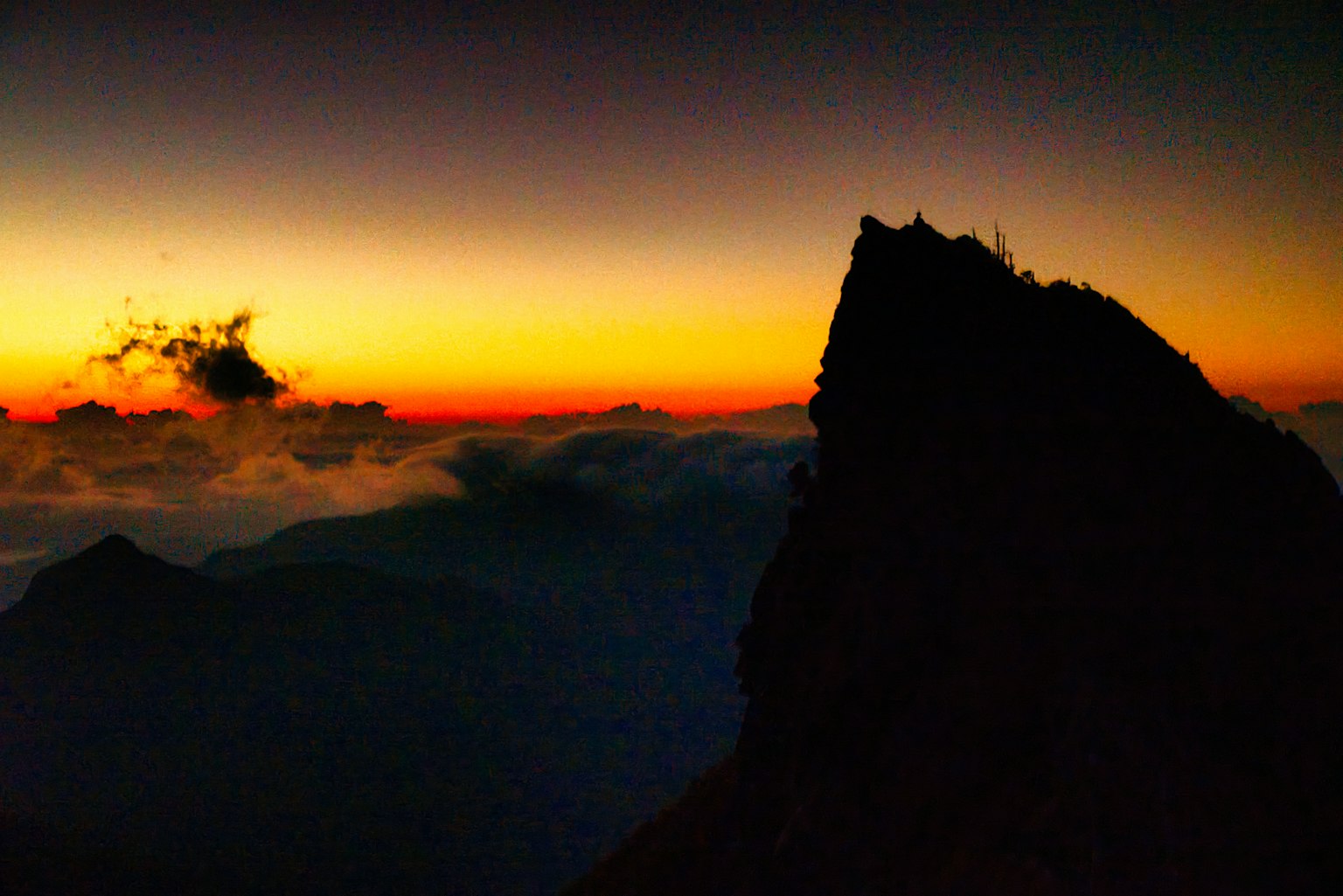 Silueta de una montaña al atardecer con nubes de fondo