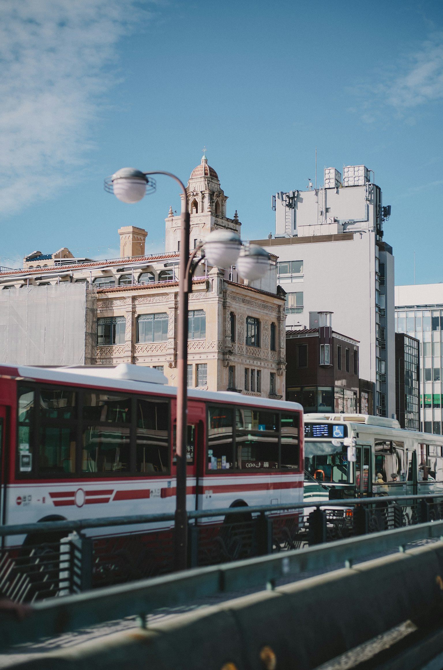 City scene with red and white buses on the street