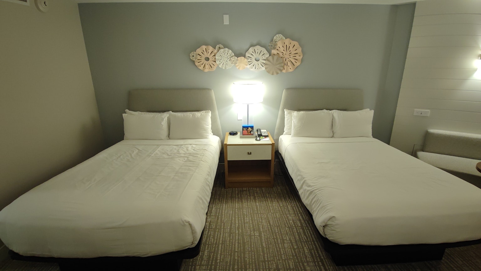 Kamar hotel modern dengan dua tempat tidur single dan meja samping