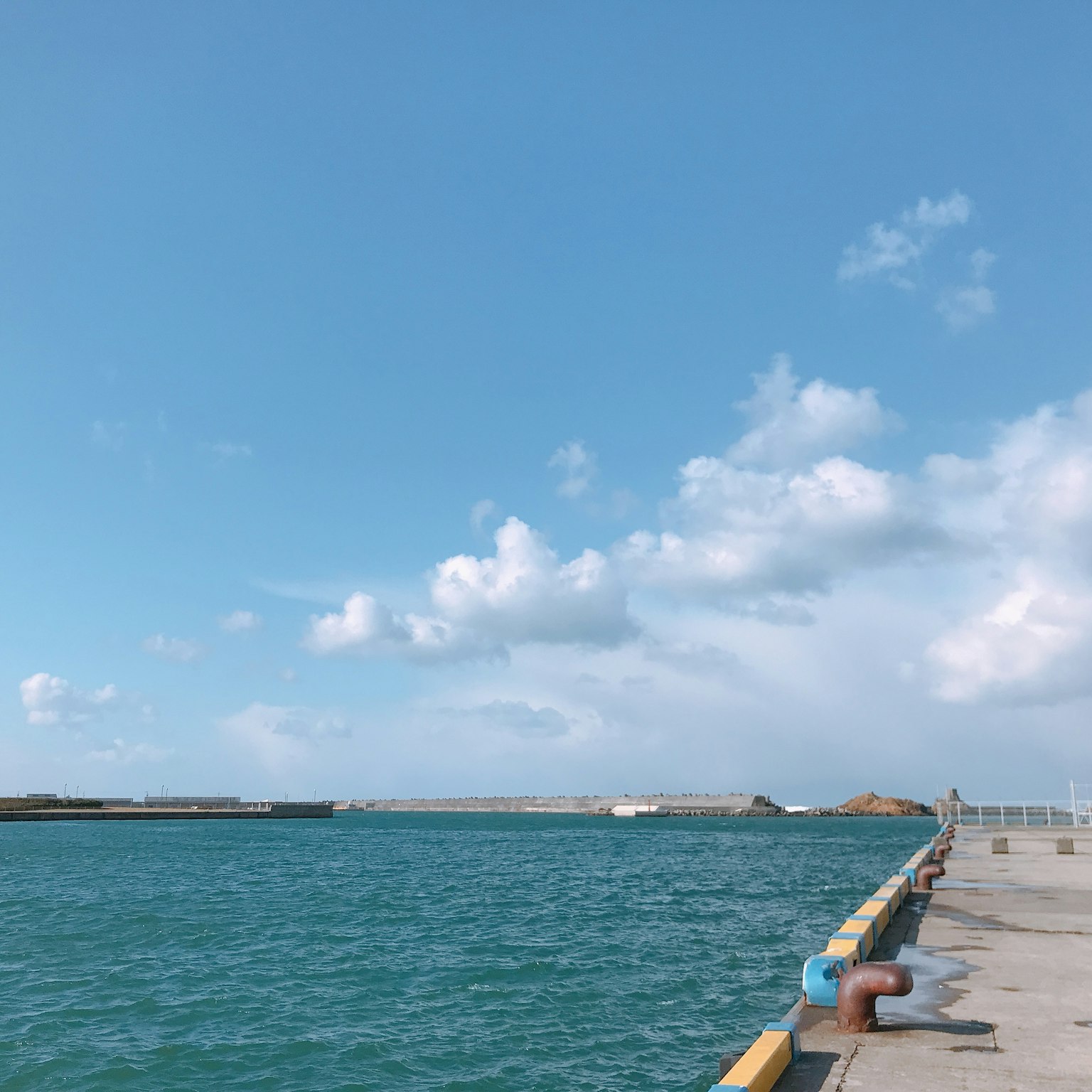 ทิวทัศน์ของท่าเทียบเรือที่ยื่นออกไปในทะเลสีฟ้าใต้ท้องฟ้าที่ปลอดโปร่ง