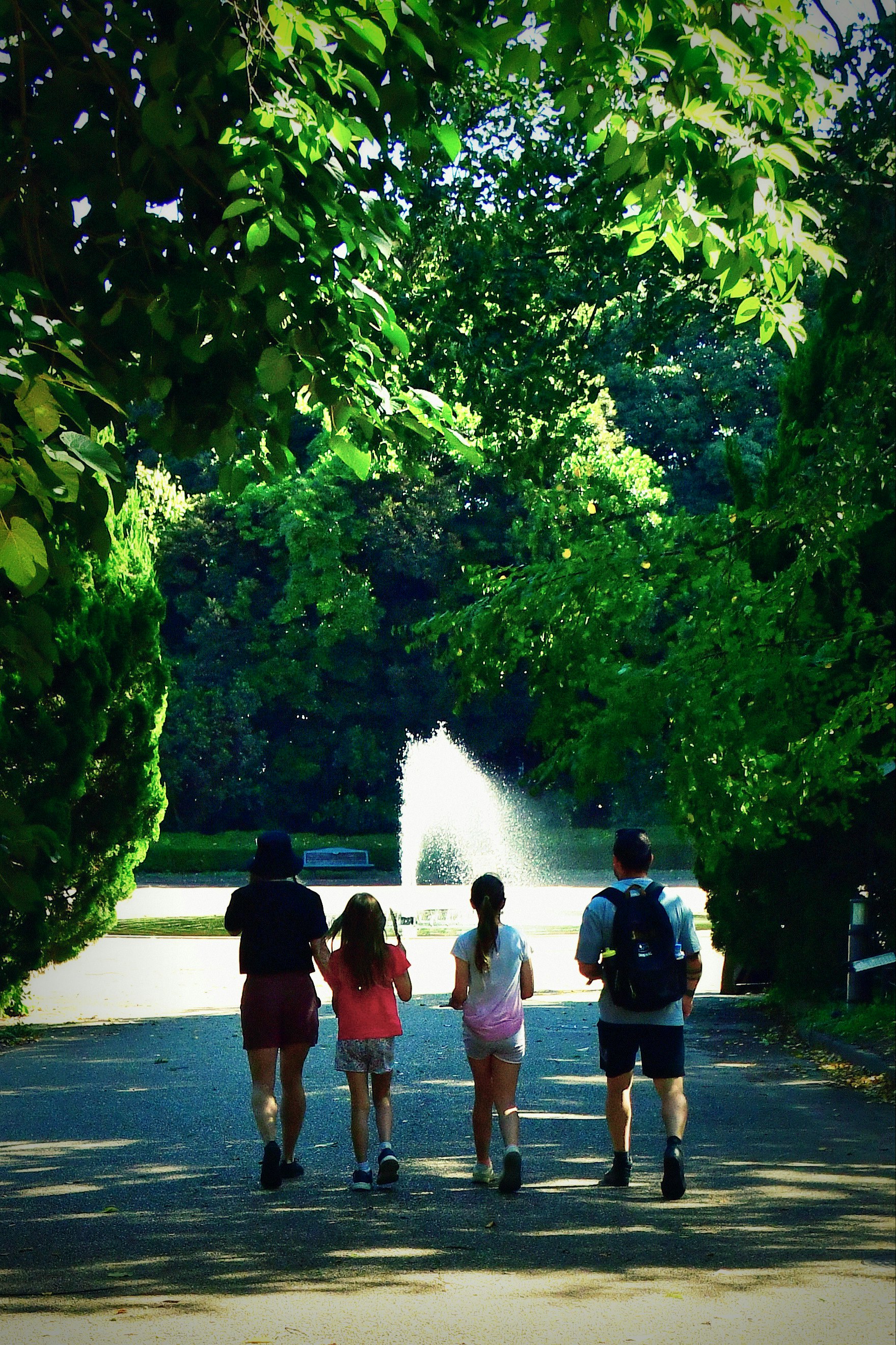 噴水のある公園で歩く家族