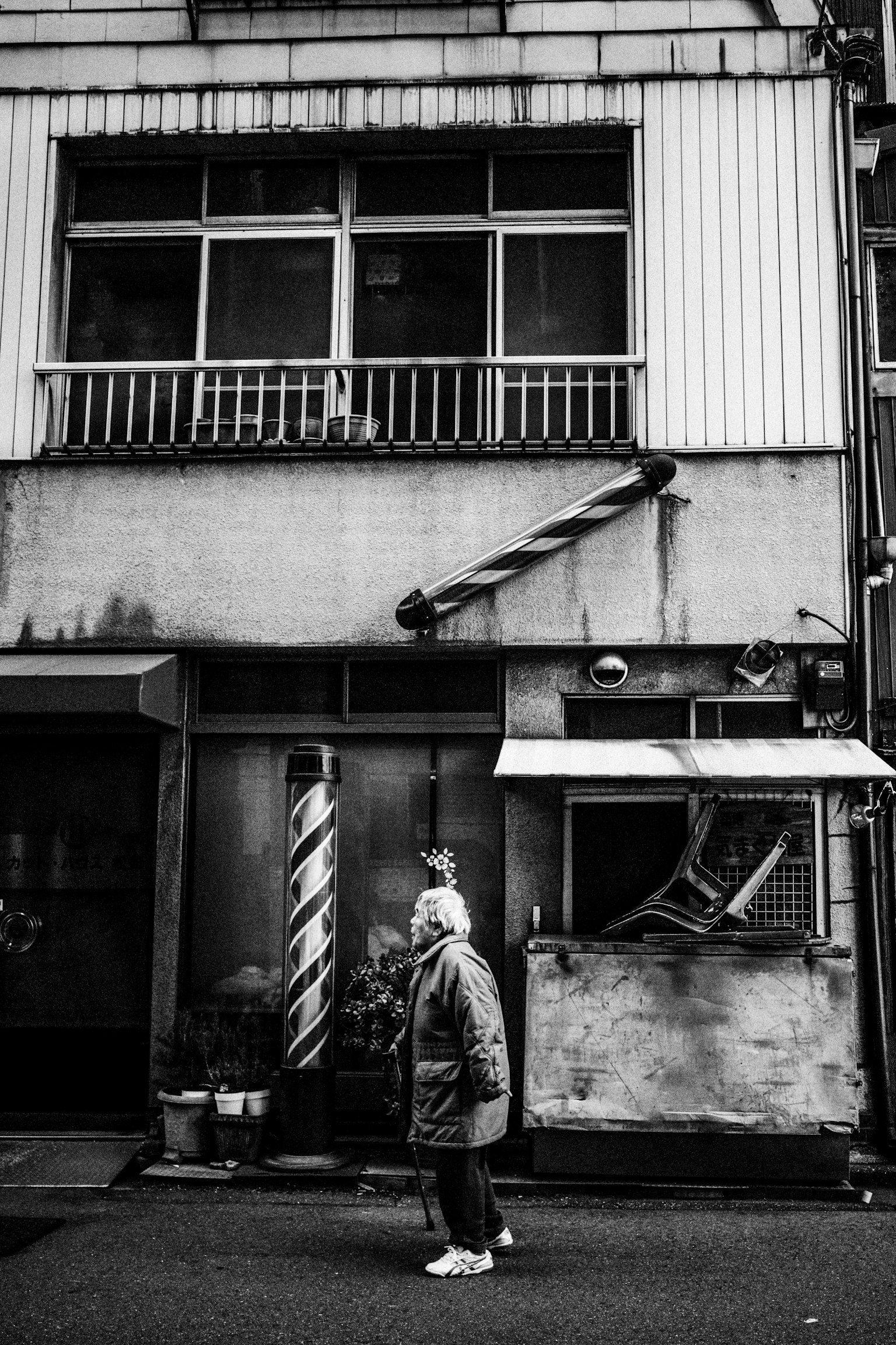 Photo en noir et blanc d'une personne marchant devant un ancien bâtiment