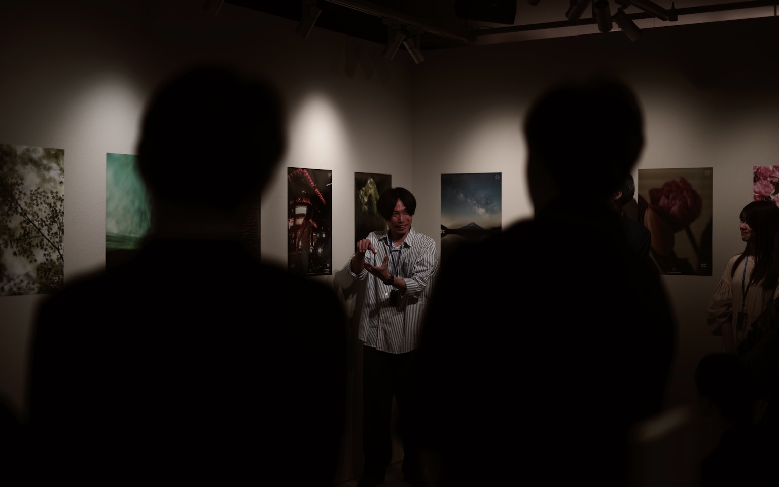 Silhouetten eines Publikums, das einen Mann beobachtet, der Kunstwerke in einer Galerie präsentiert