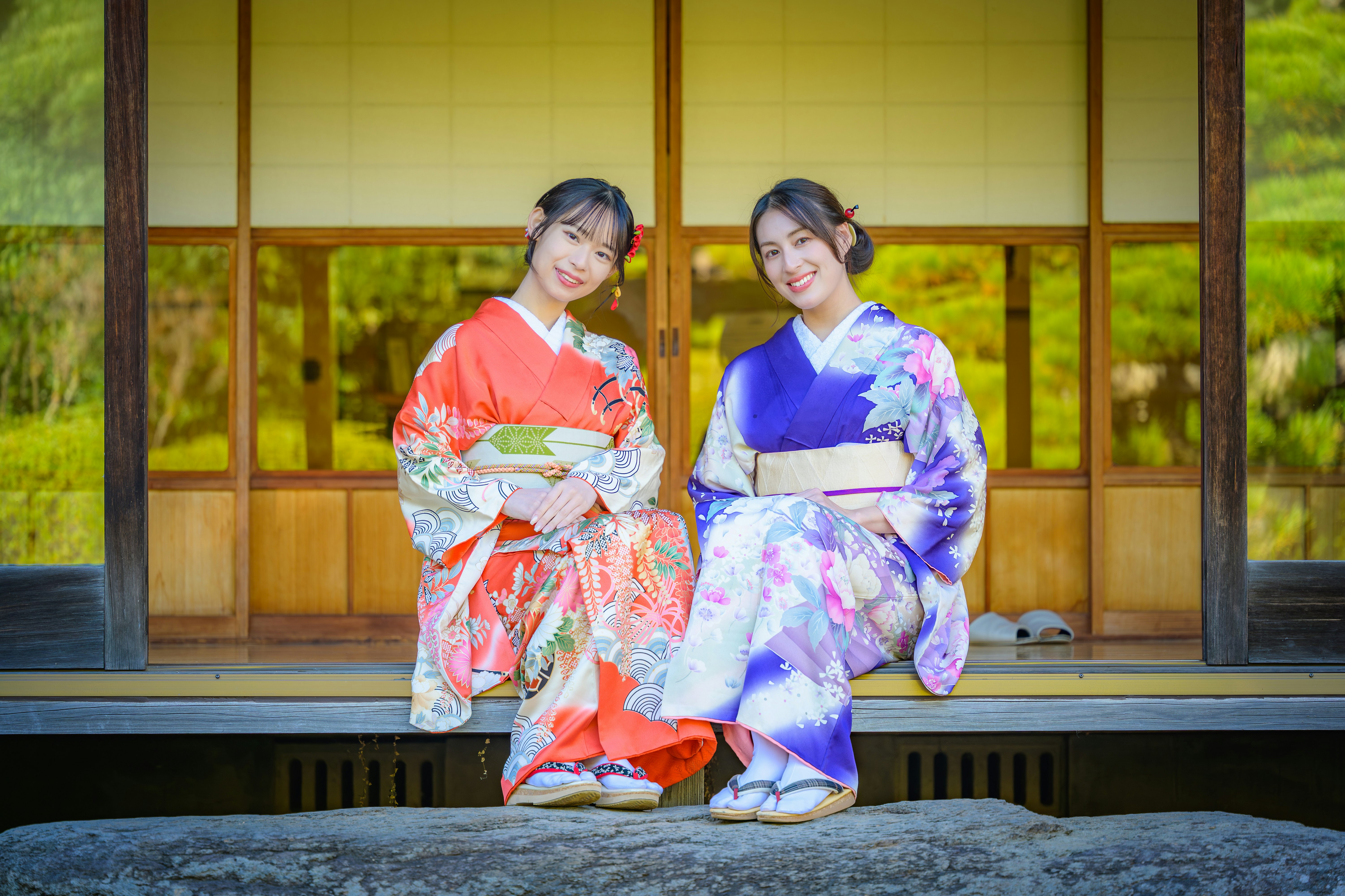 Zwei Frauen in farbenfrohen Kimonos sitzen auf einer Engawa-Veranda