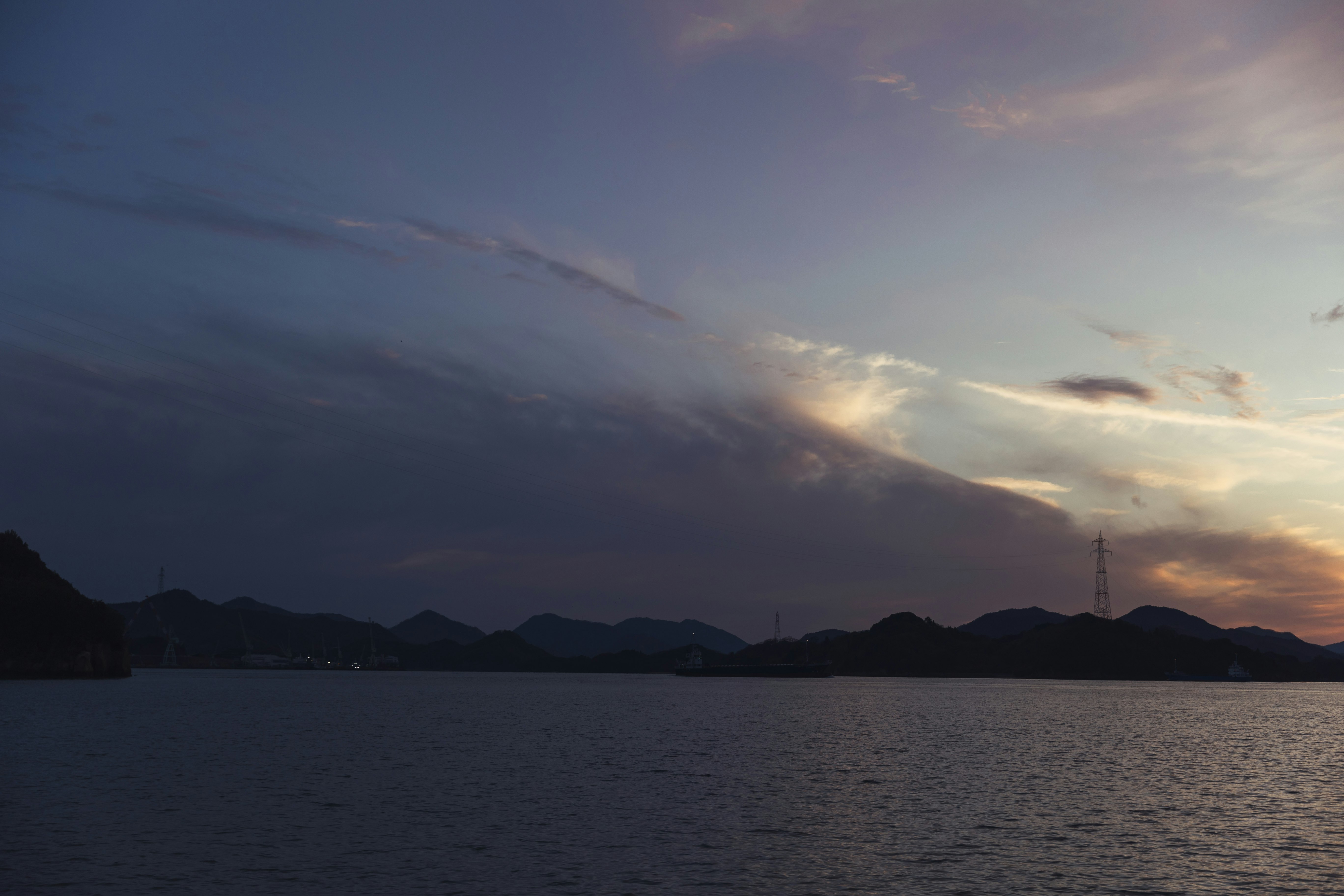 sunset over a lakeside with mountain silhouettes and horizon