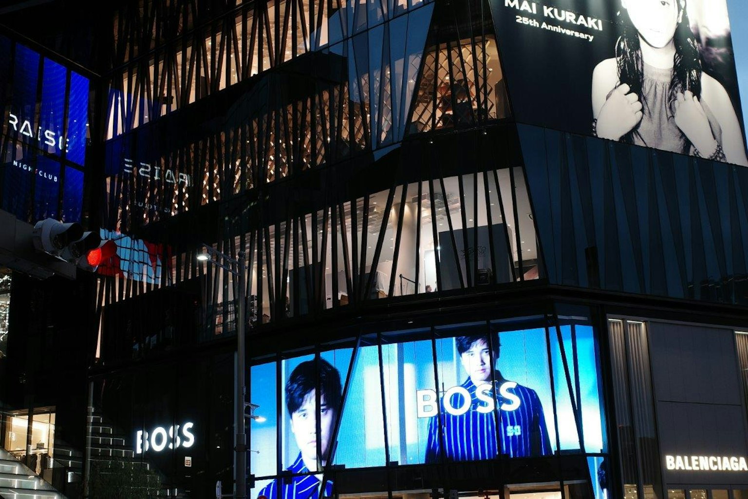 A modern building at night featuring prominent BOSS advertisements