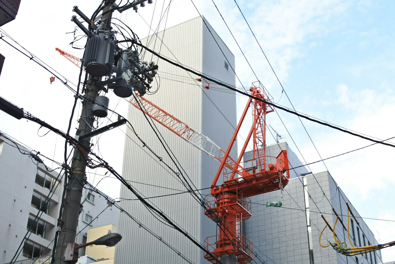 城市景观，展示一个施工现场和一台大型橙色起重机