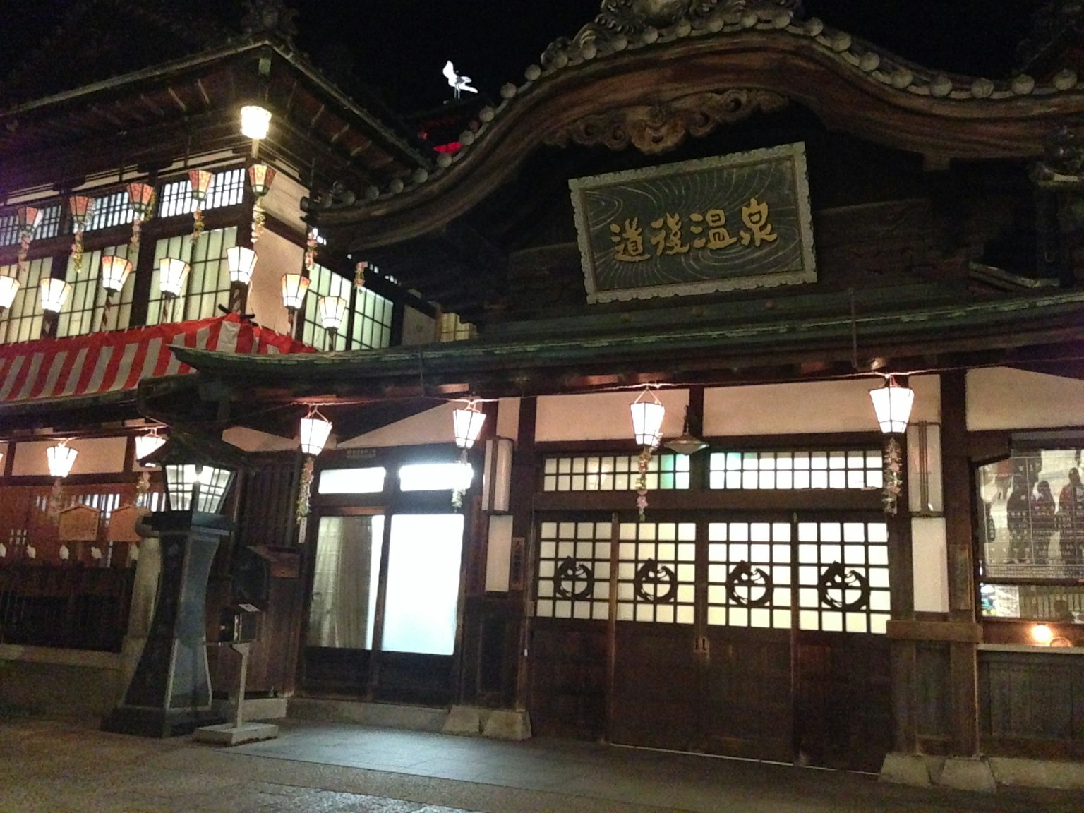 夜間傳統日本旅館外觀，帶有照明窗戶和裝飾性屋頂