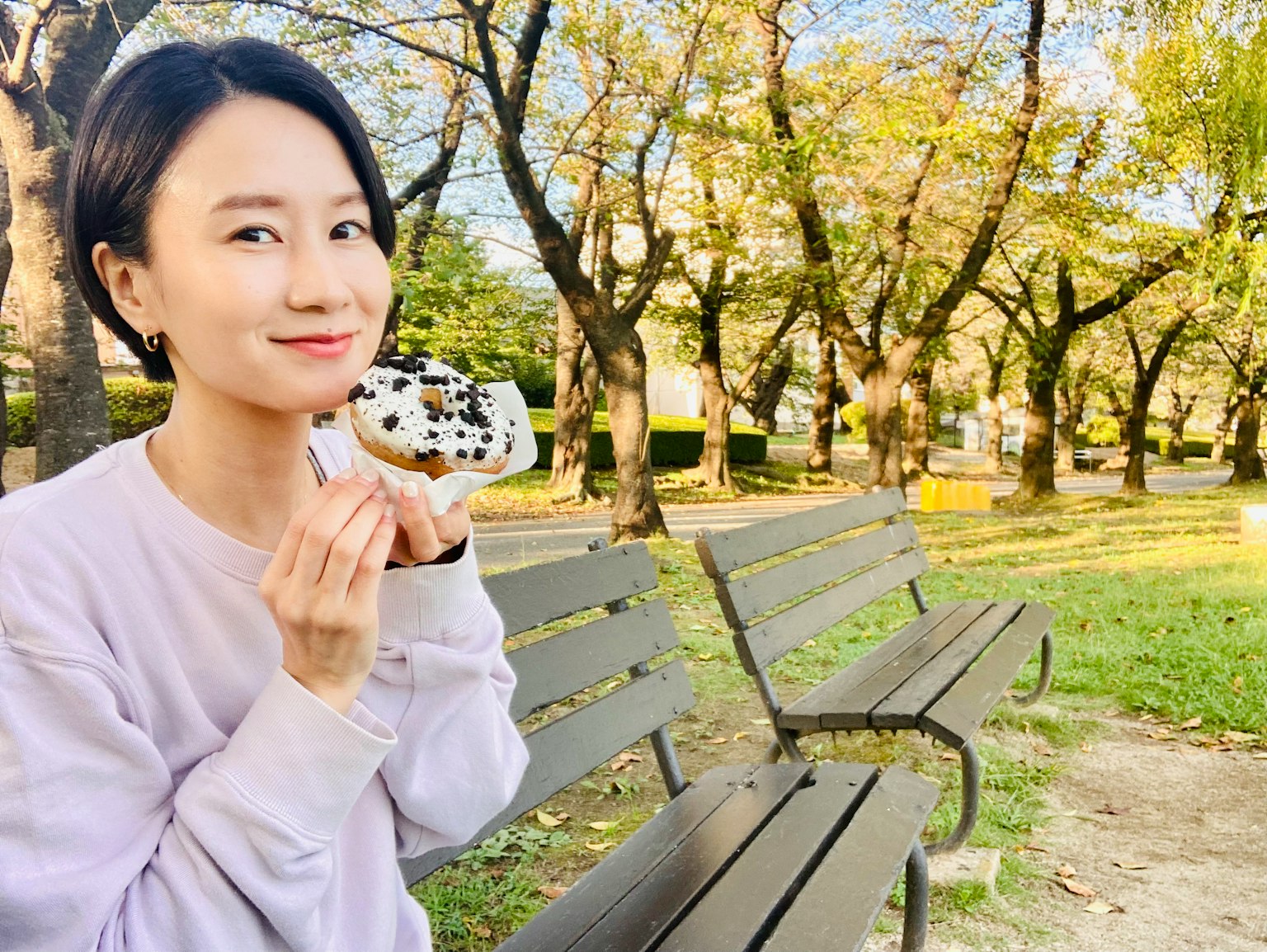 Donna sorridente che tiene un dessert in un parco