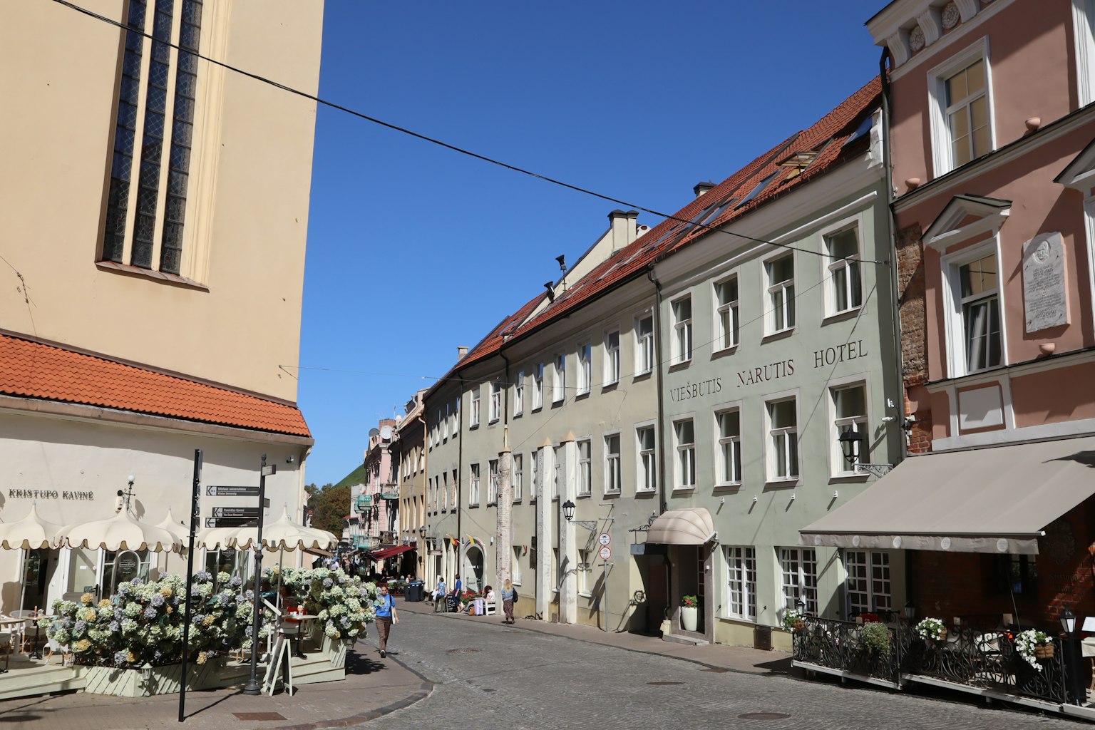 Bunte Gebäude und Cafés entlang einer historischen Straße unter blauem Himmel