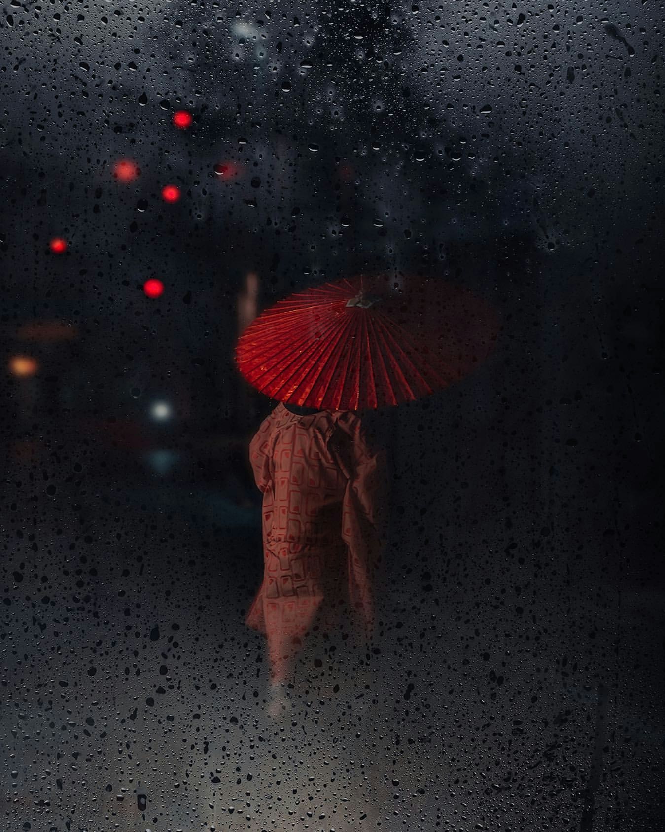 Bóng người cầm ô đỏ nhìn qua cửa sổ đầy mưa