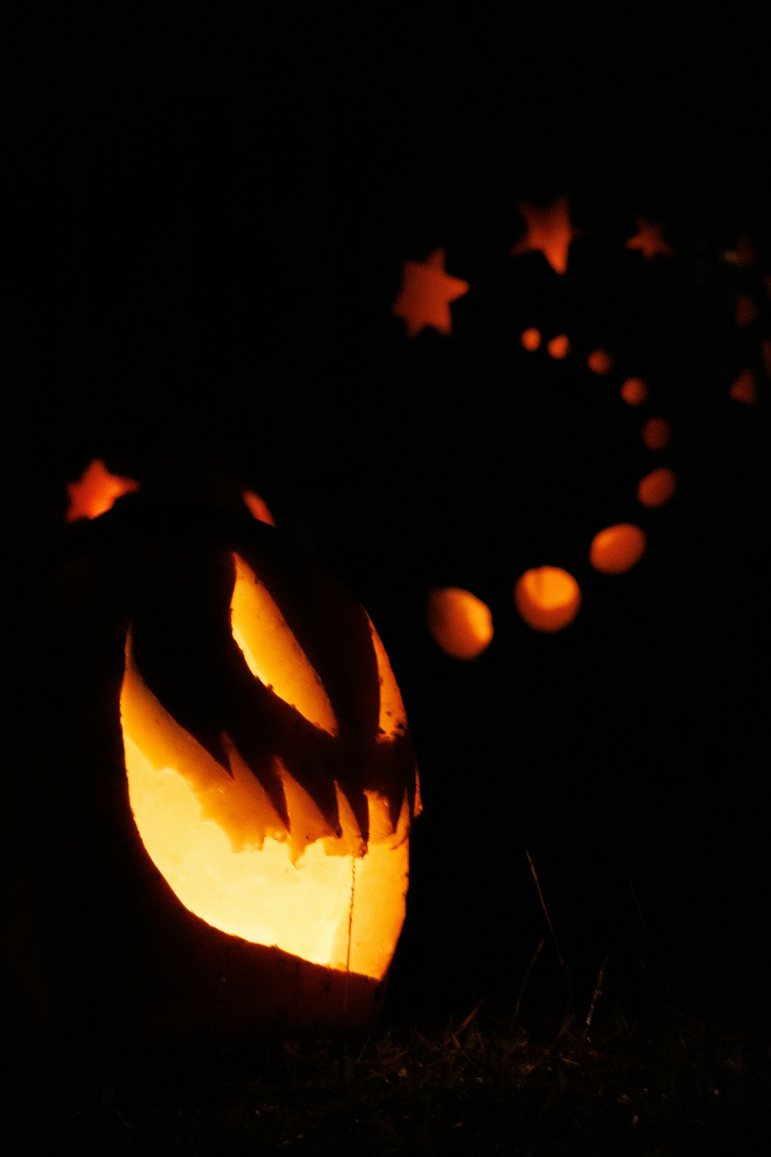 暗闇の中で輝くジャック・オー・ランタンと星形の光の連なり