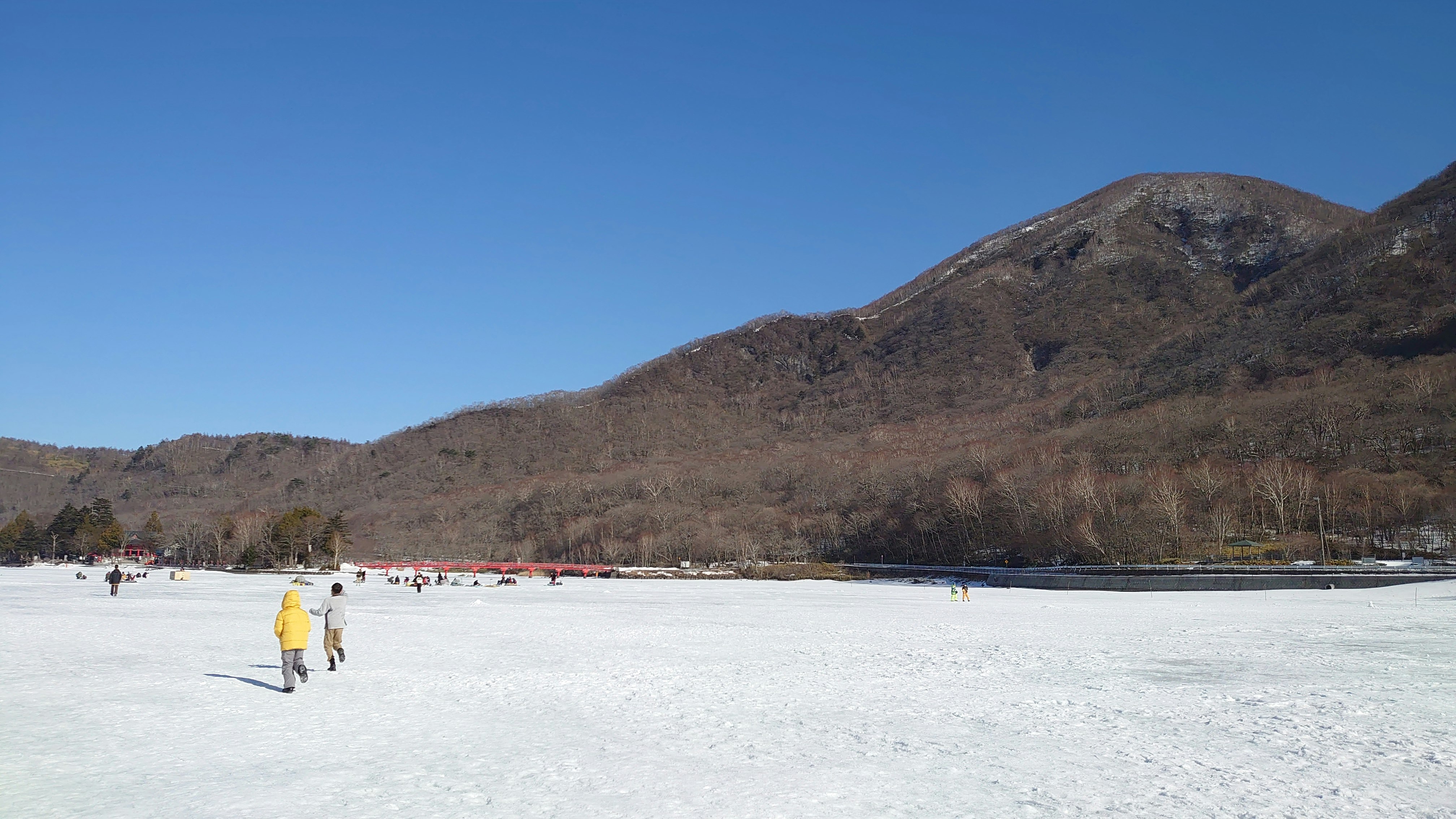 群馬県の赤城大沼で氷上ワカサギ釣りをする人々と青空
