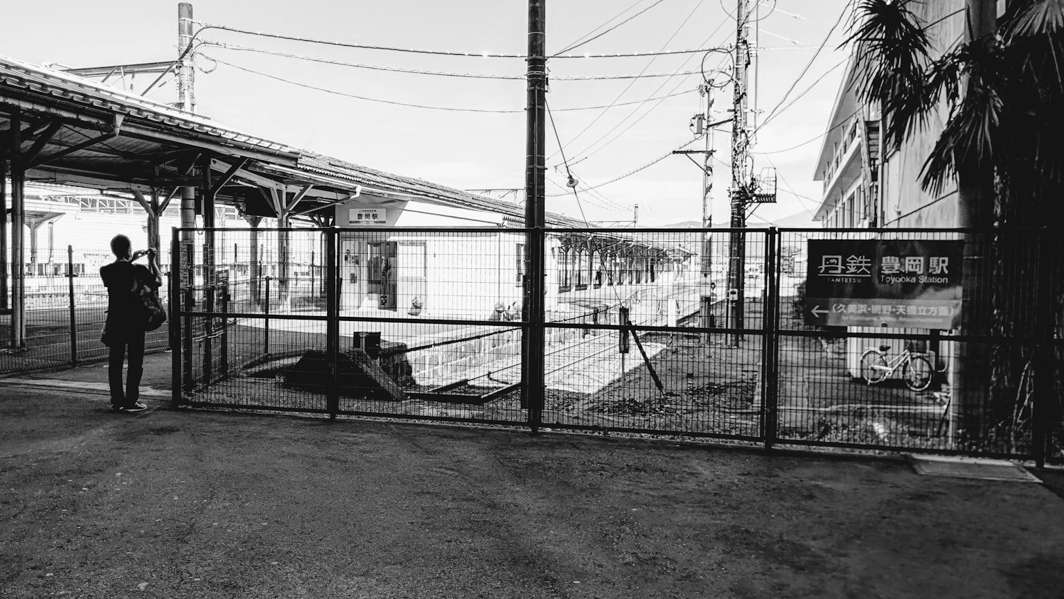 Une personne se tenant près des voies avec une clôture à une gare