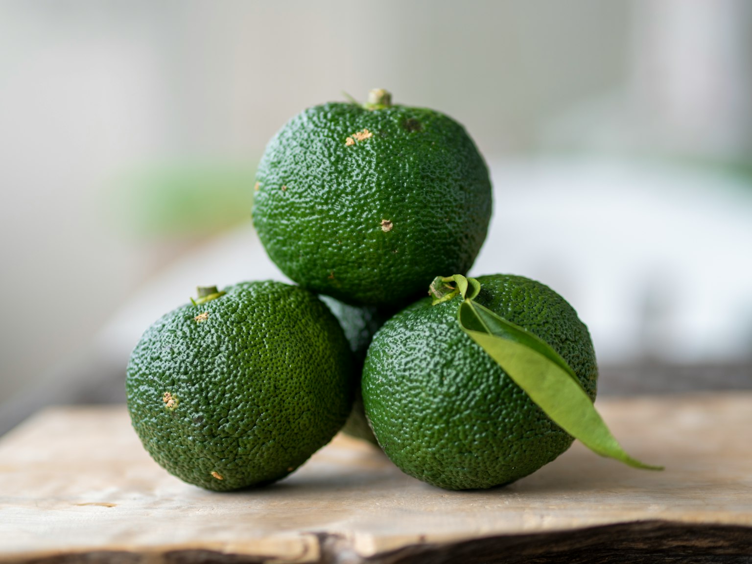 Tres aguacates verdes apilados sobre una tabla de madera