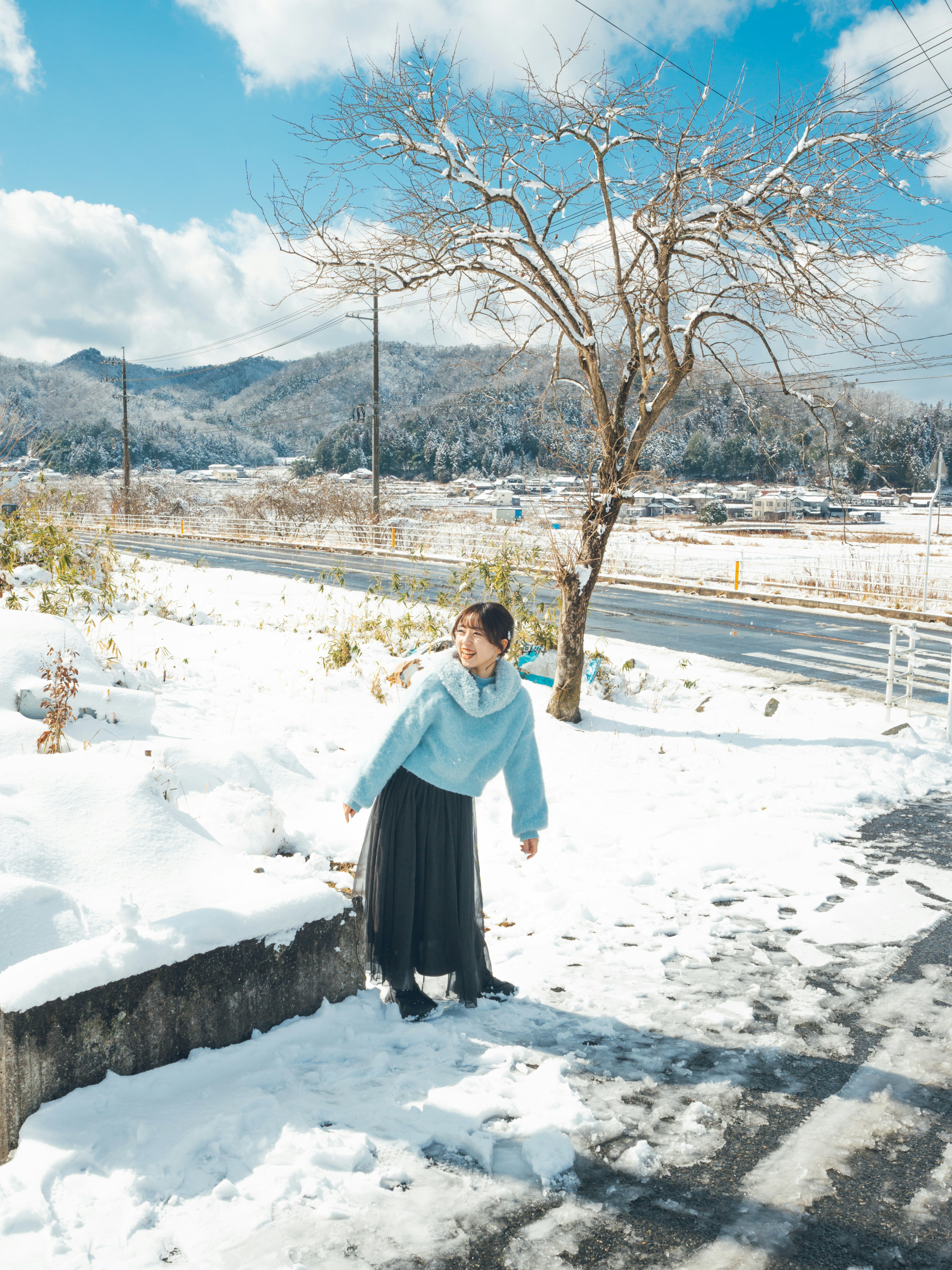 雪景色の川沿いで木のそばに立つ人物