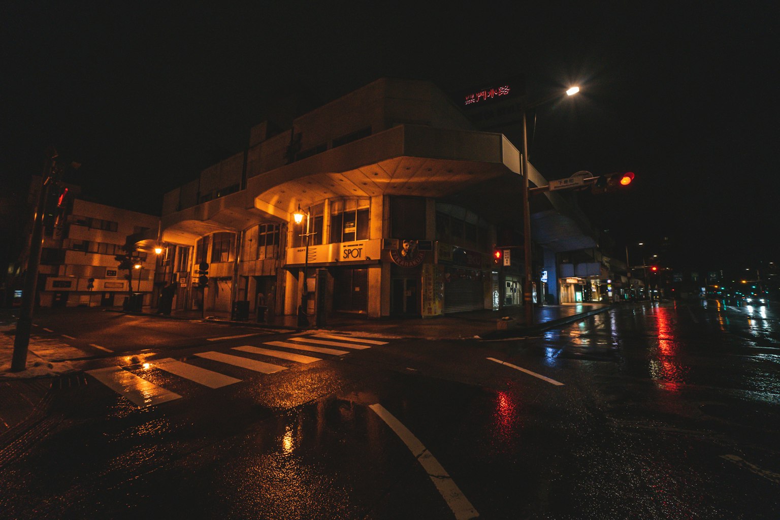 Coin de rue mouillé la nuit avec des bâtiments éclairés et des feux de circulation