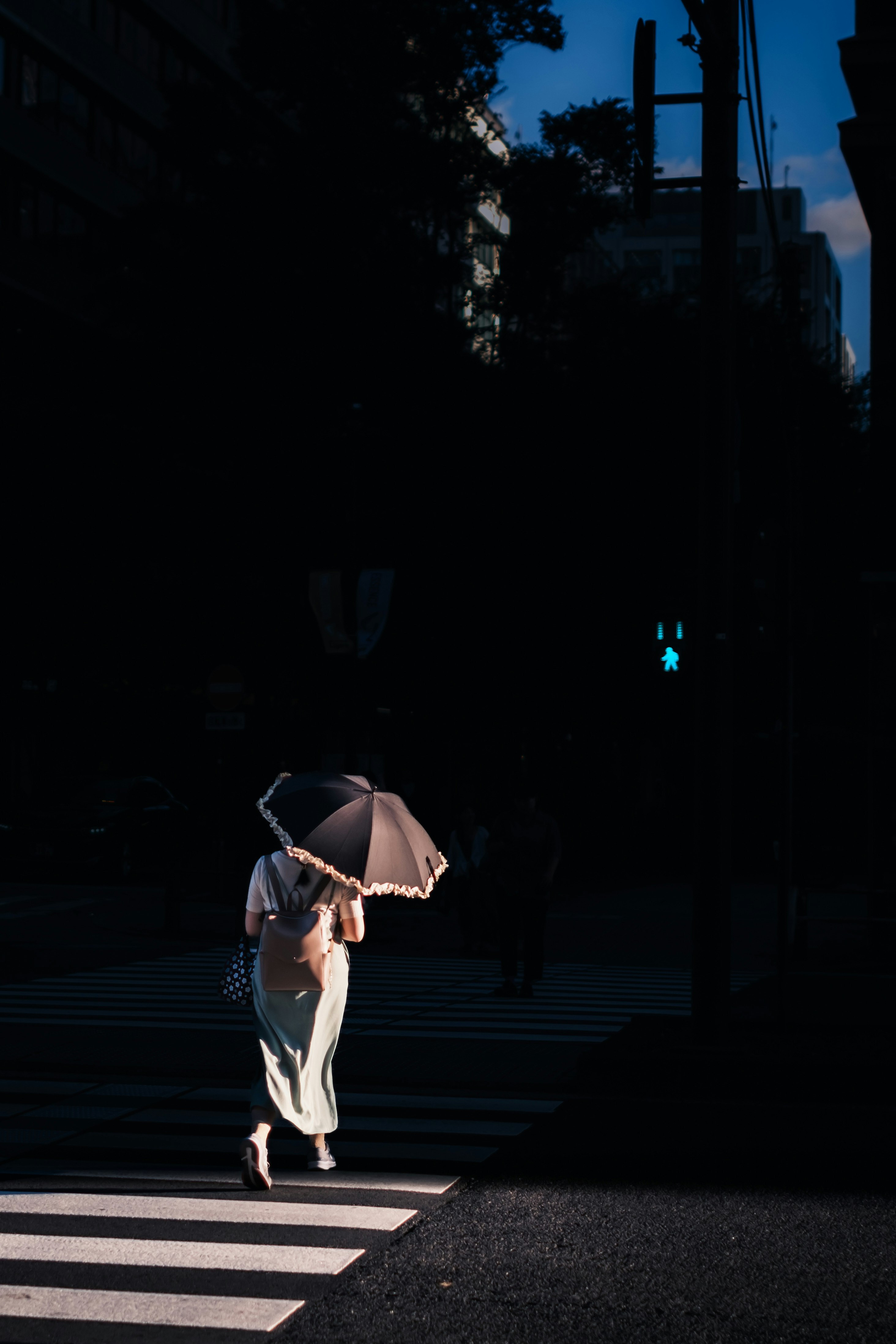 夕暮れの路地を歩く傘の人物