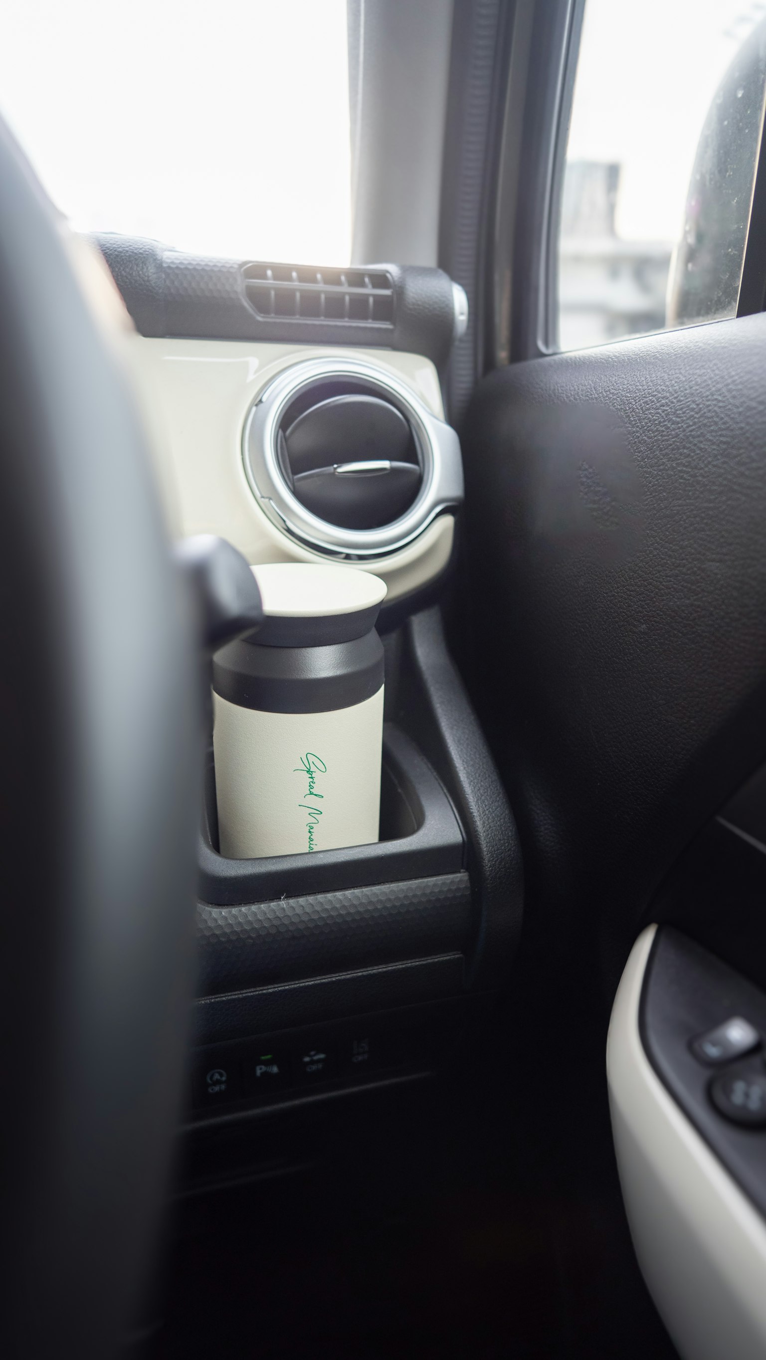 Gobelet blanc dans un porte-gobelet de voiture avec une partie du tableau de bord visible