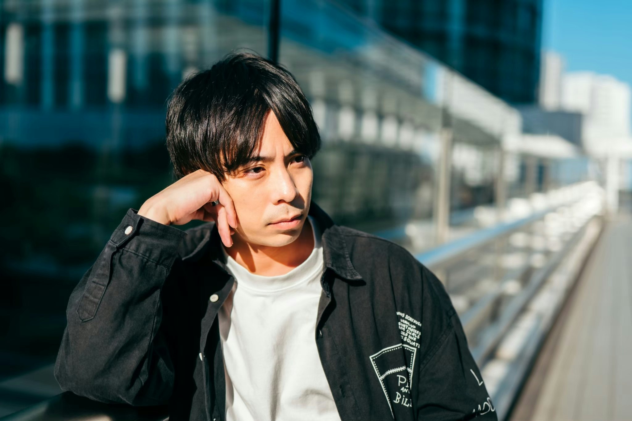 屋外の階段で手を首元に添える男性