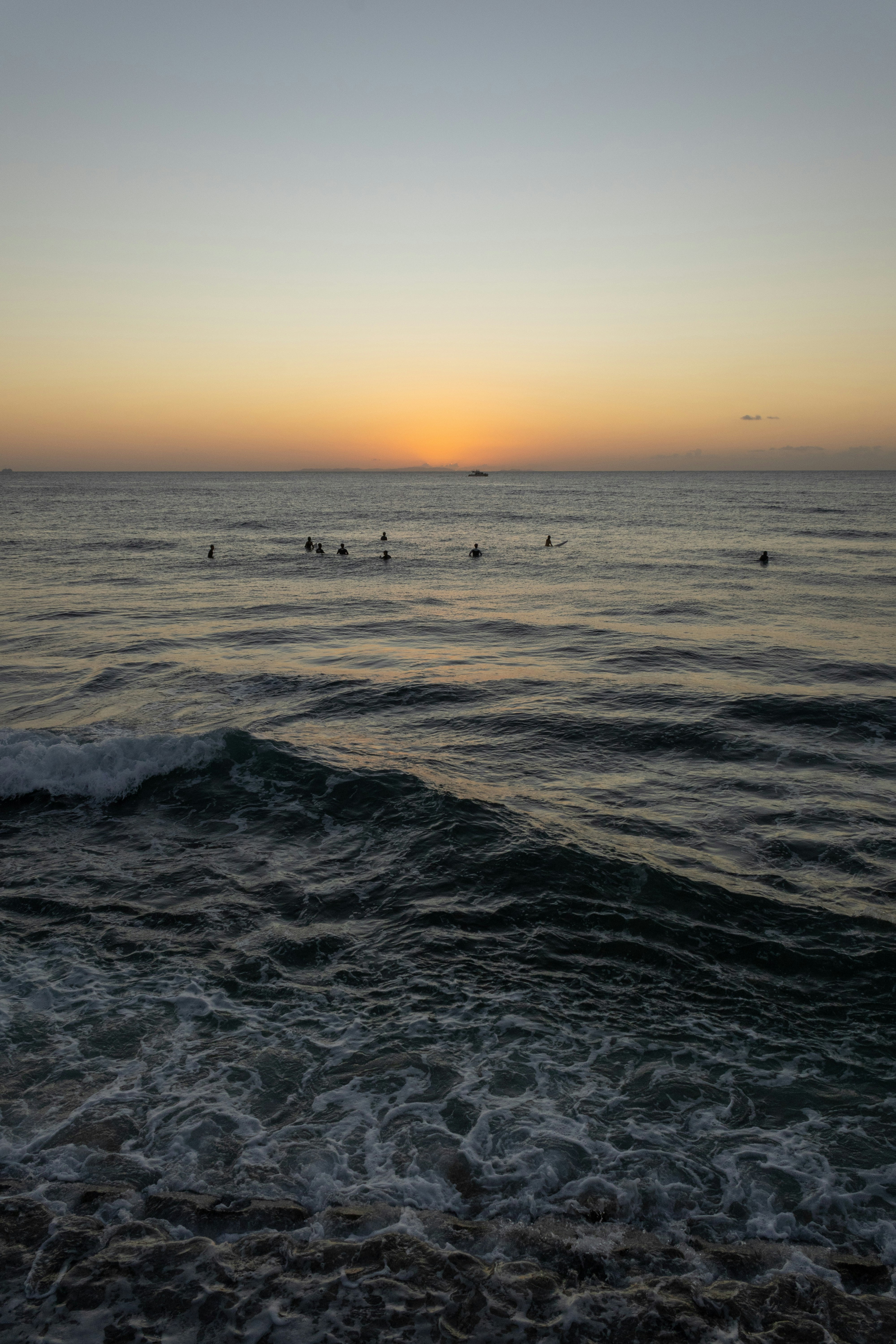 Paisaje de Okinawa al atardecer sobre el mar, con personas caminando por la orilla