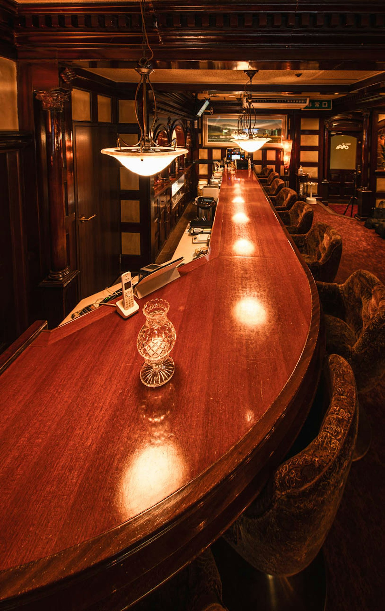 Interior de bar clásico con un largo mostrador de madera y luz ambiental