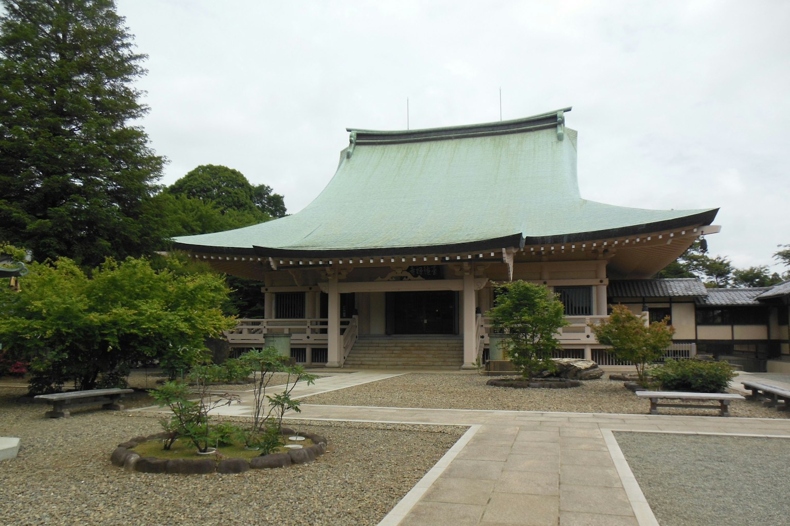 Bangunan tradisional Jepang dengan atap hijau dikelilingi taman