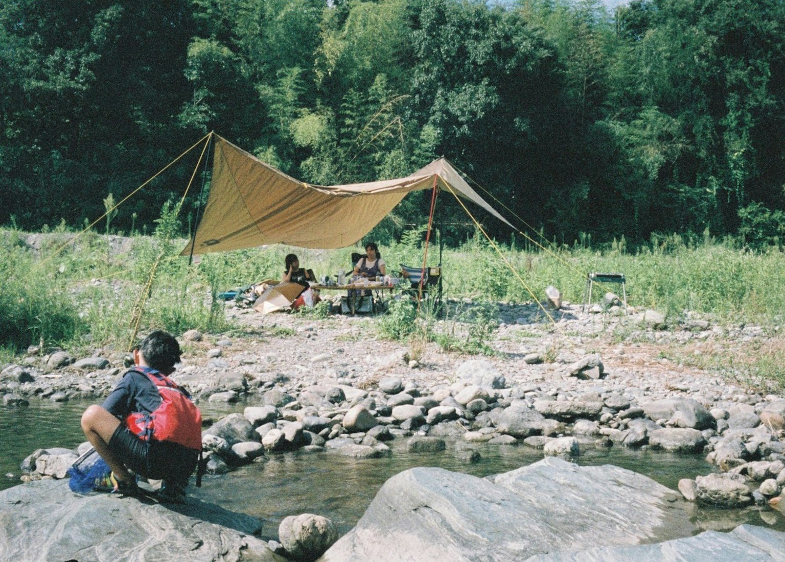 Orang-orang berkemah di tepi sungai dengan tenda
