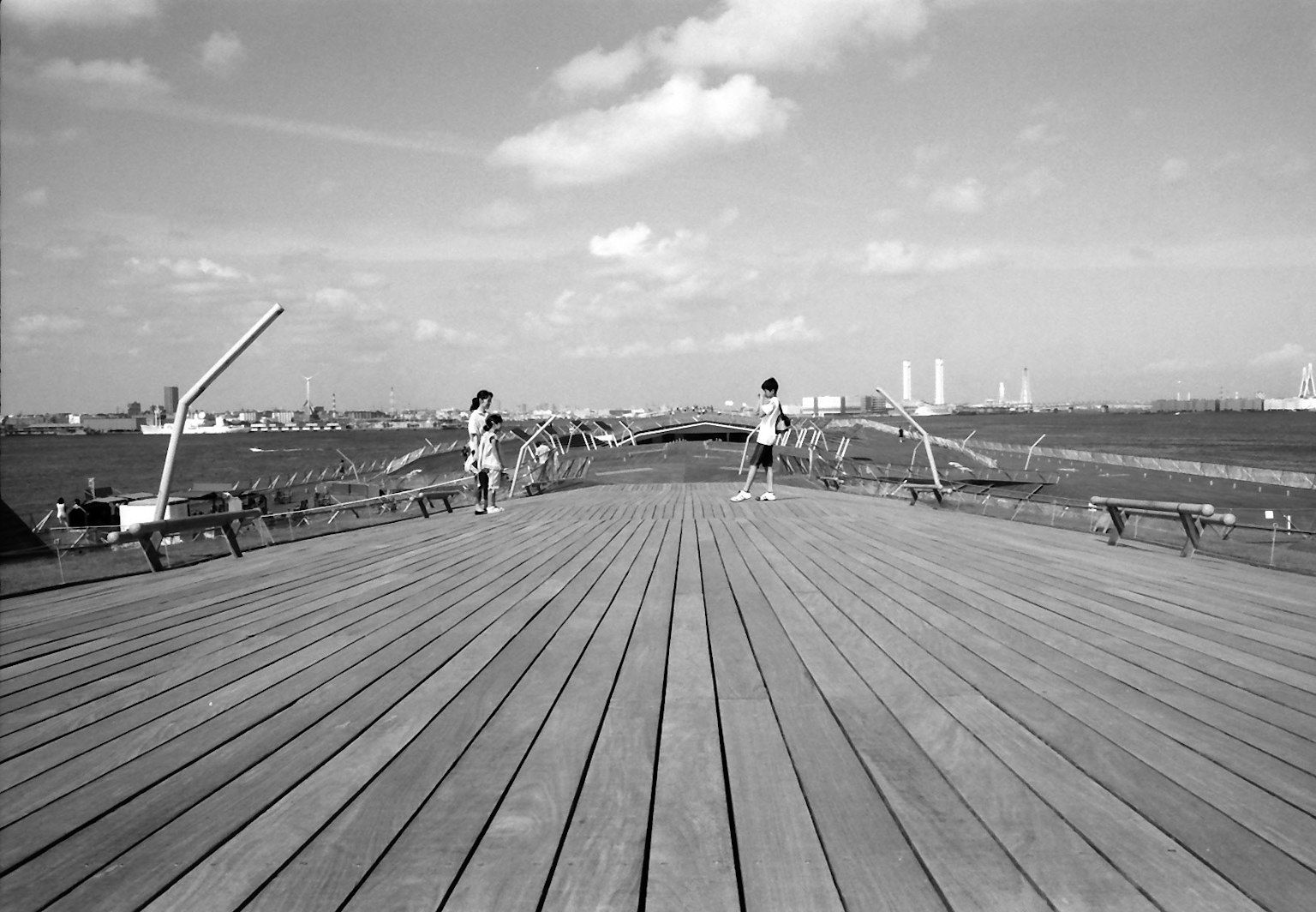 Image en noir et blanc de deux personnes sur une terrasse en bois avec une ligne d'horizon urbaine en arrière-plan