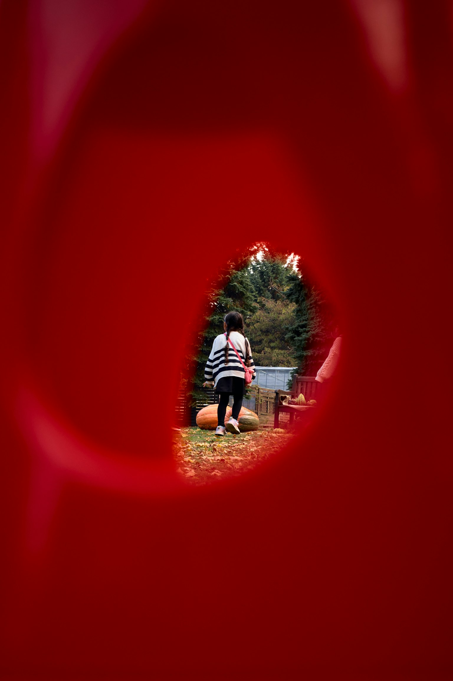 赤い遊具の間から見える女性が公園で遊んでいる様子