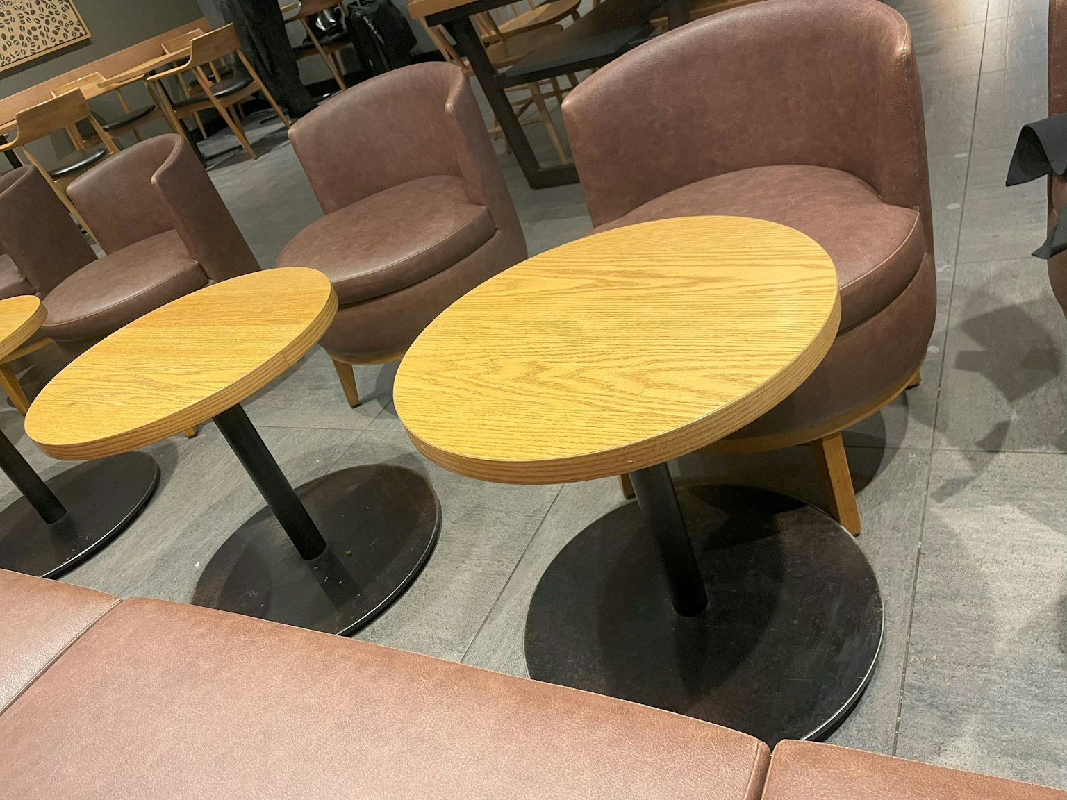 Tables rondes en bois et chaises en cuir dans un intérieur de café