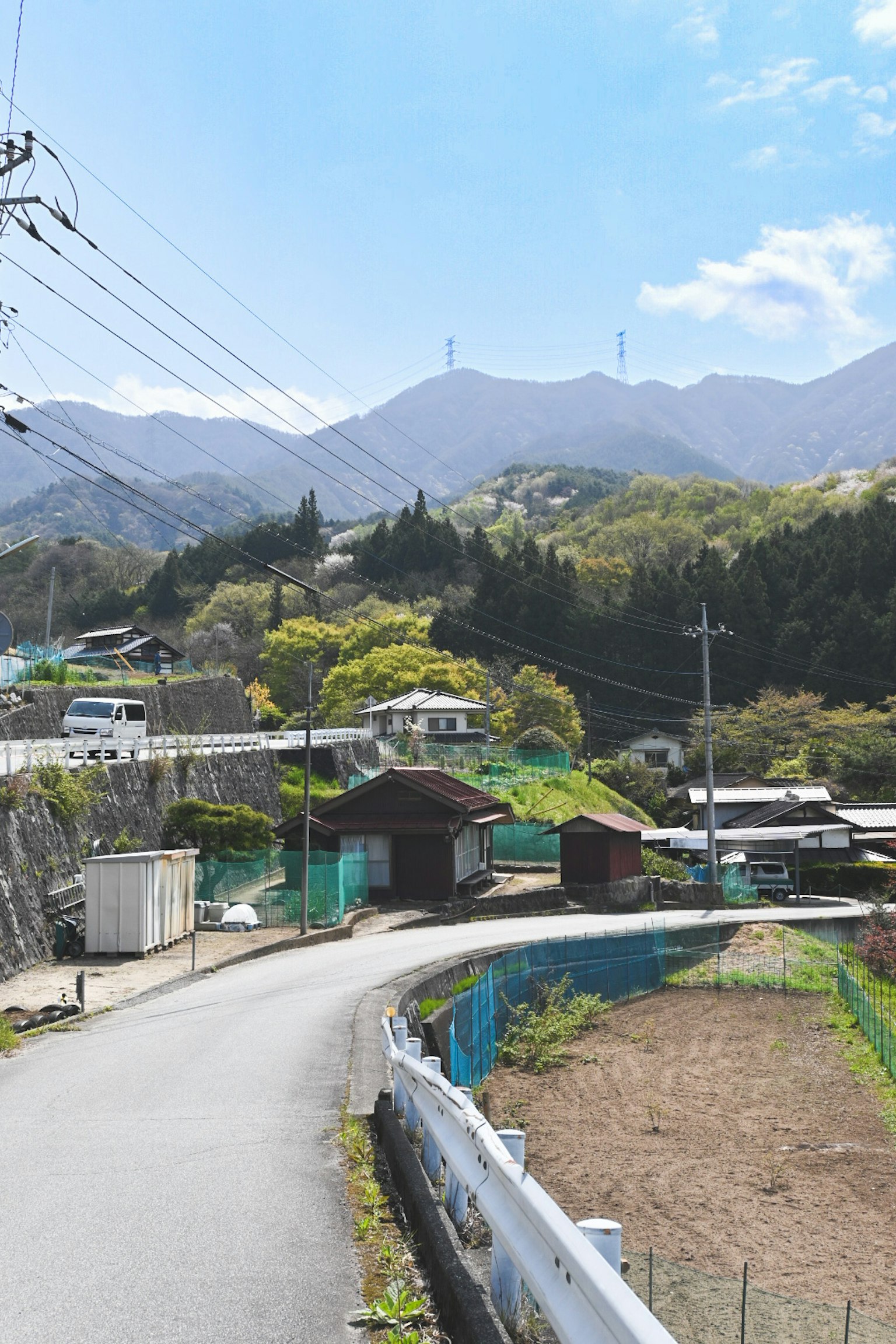 Un paisaje de aldea tranquilo rodeado de montañas con vegetación exuberante y un cielo azul