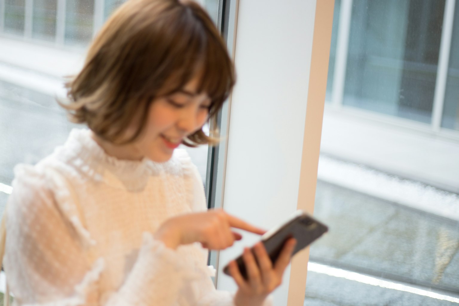 Una donna che usa uno smartphone vicino alla finestra