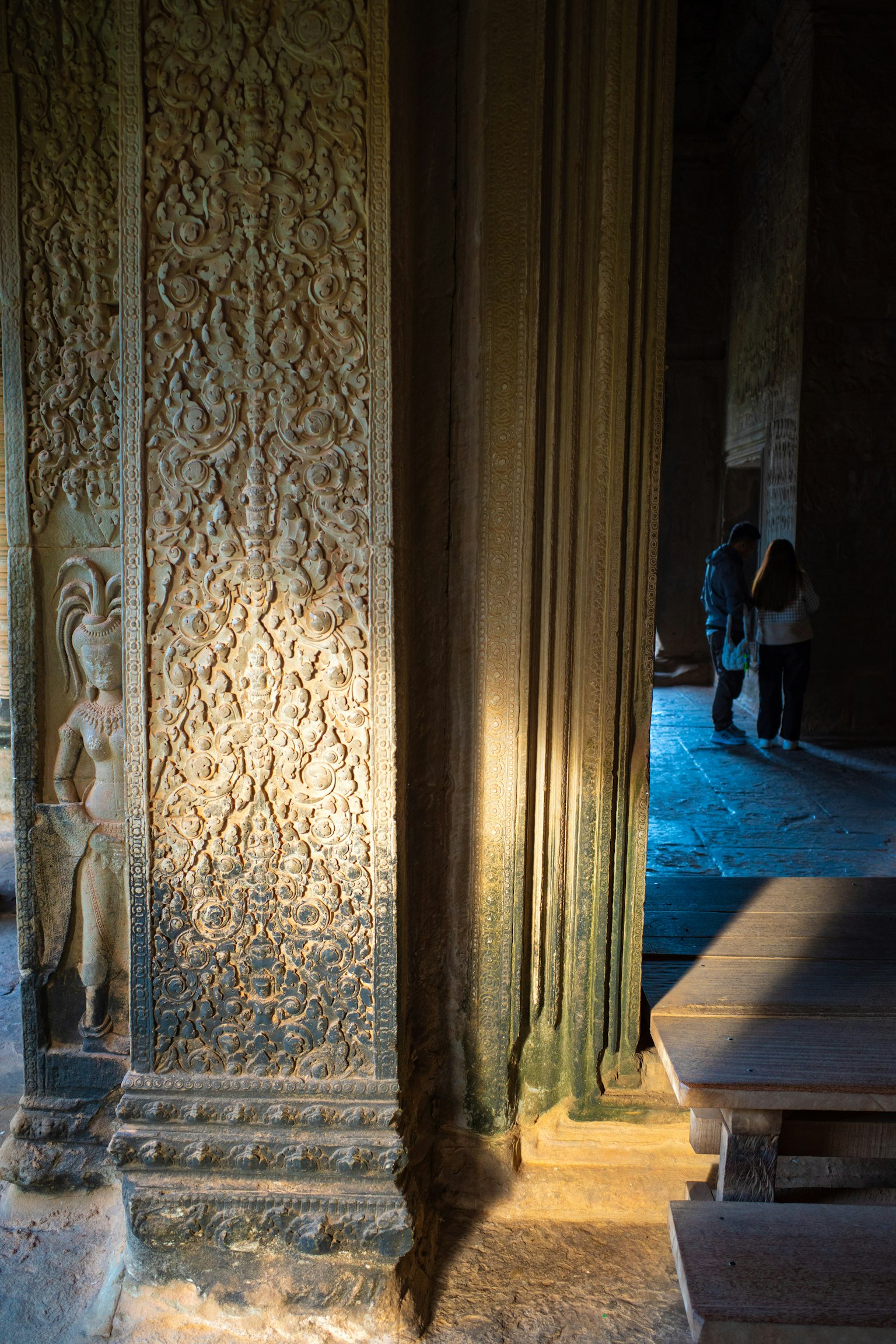 Carved pillar in a dim space with blue light illuminating the area