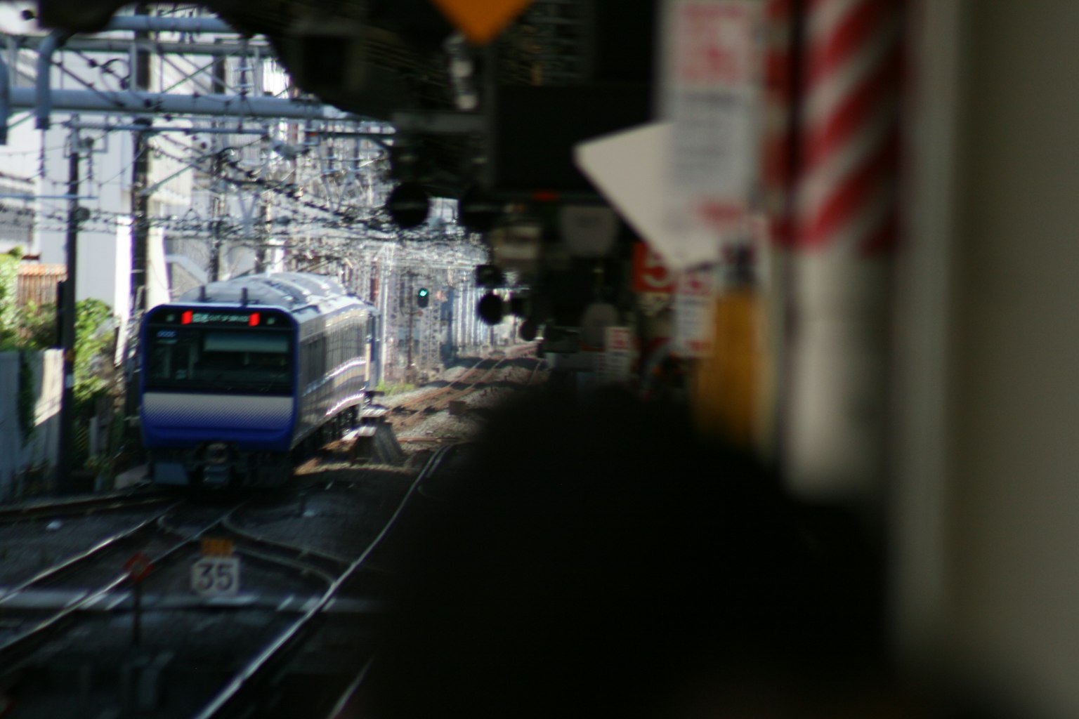 Un treno che corre su binari con cavi aerei e edifici circostanti
